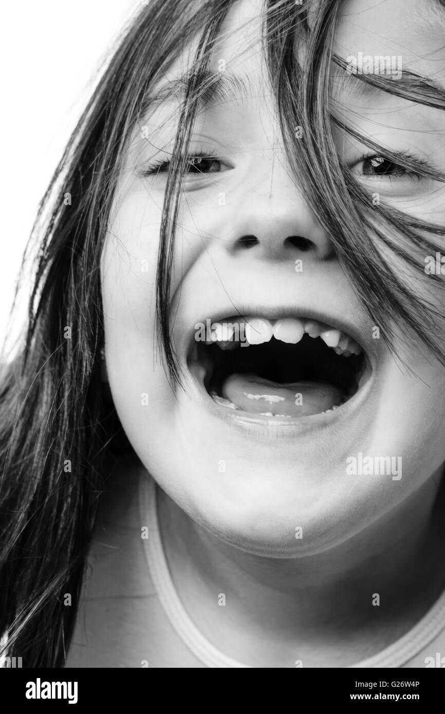 Close up portrait of a cute young girl loudly laughing isolated on white background Stock Photo