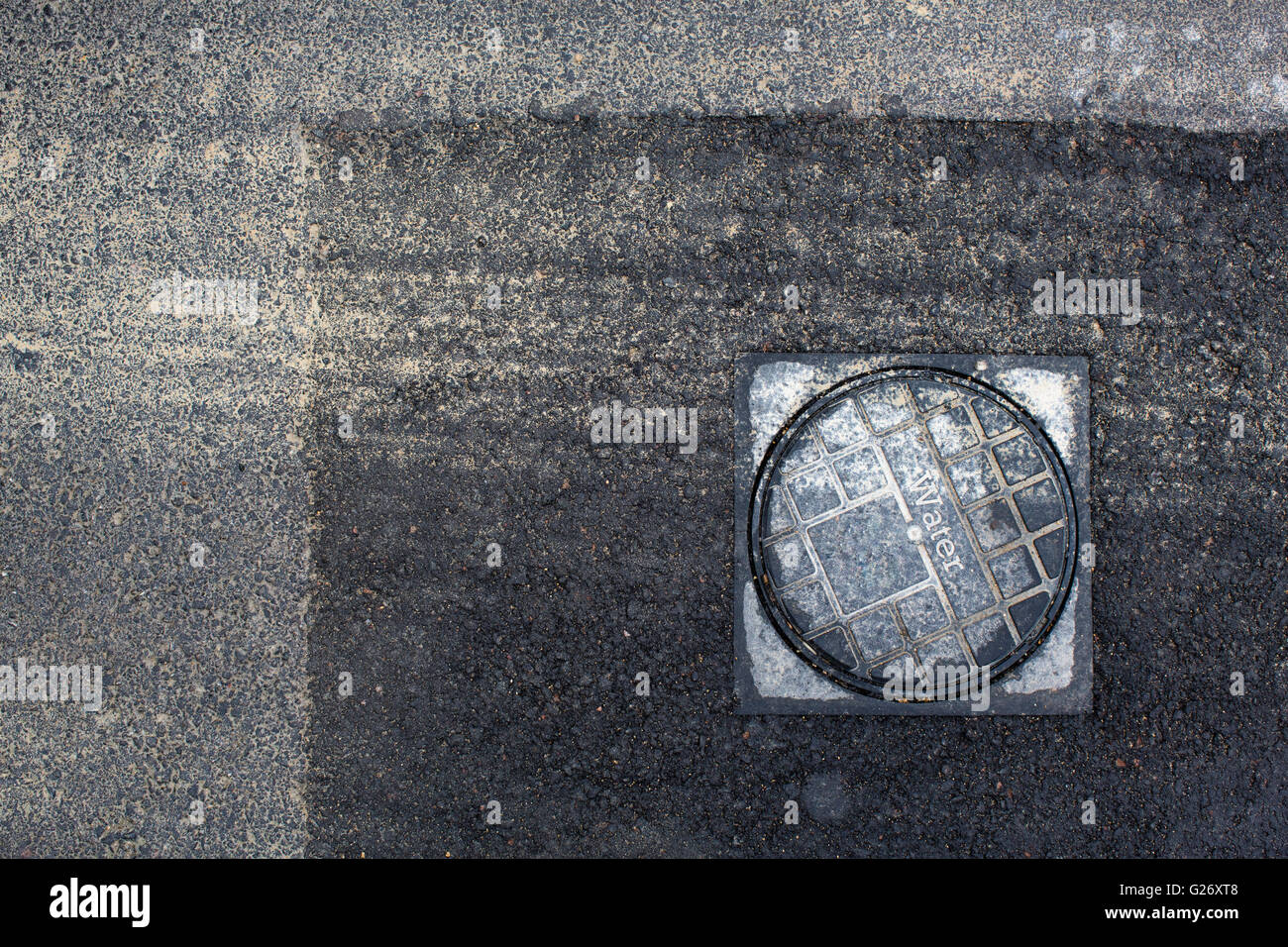 Covers set in the road hiding access to water and utilites for domestic housing. Stock Photo