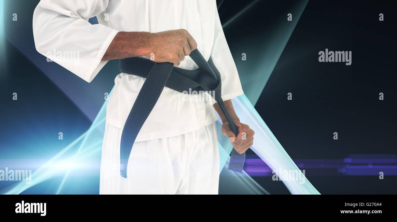 Composite image of fighter tightening karate belt Stock Photo