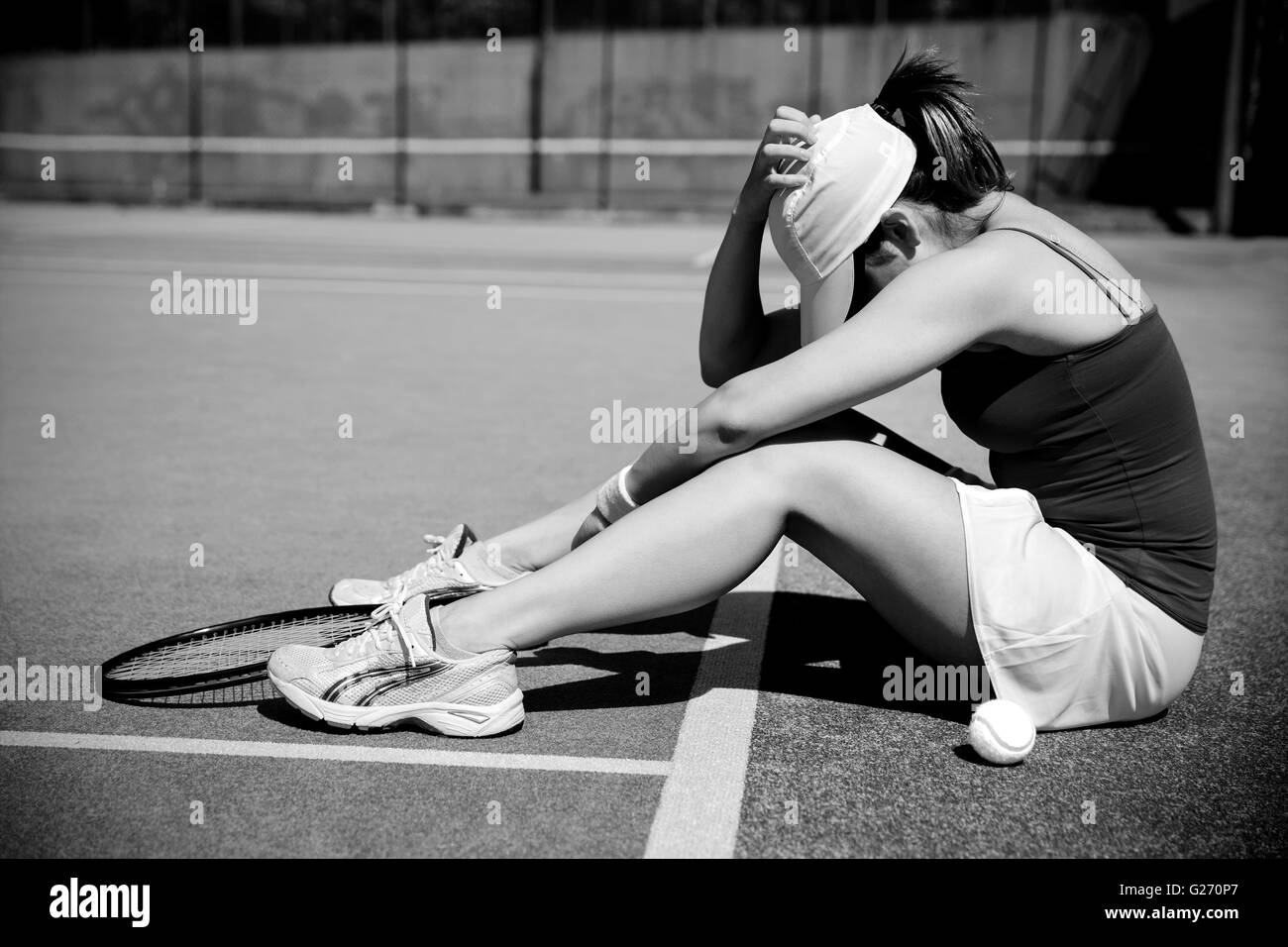 Upset tennis player sitting on court Stock Photo