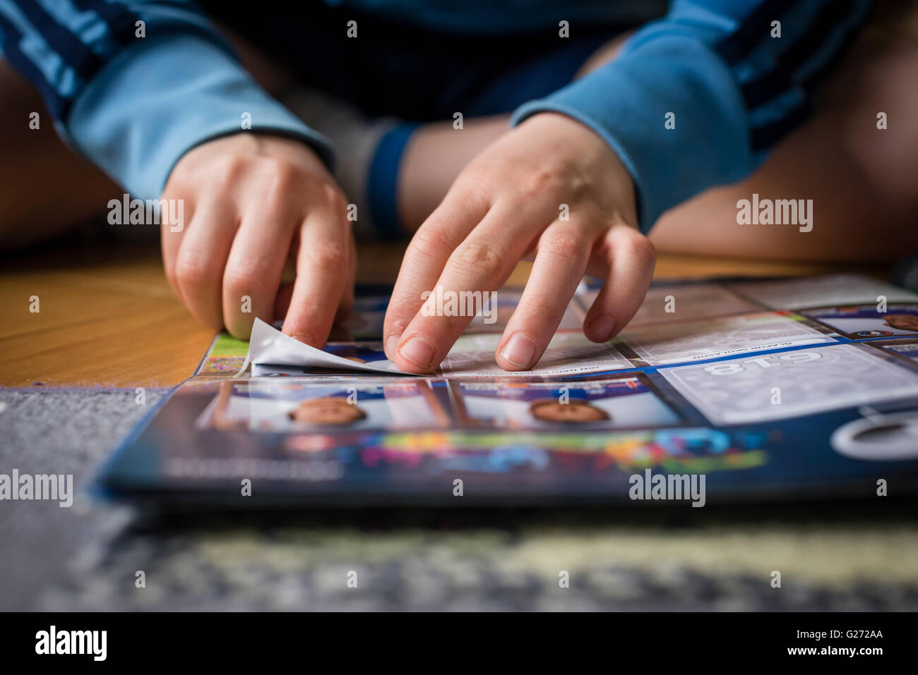 An 8 year old boy is pasting football trading cards into his sticker collection scrapbook. Stock Photo