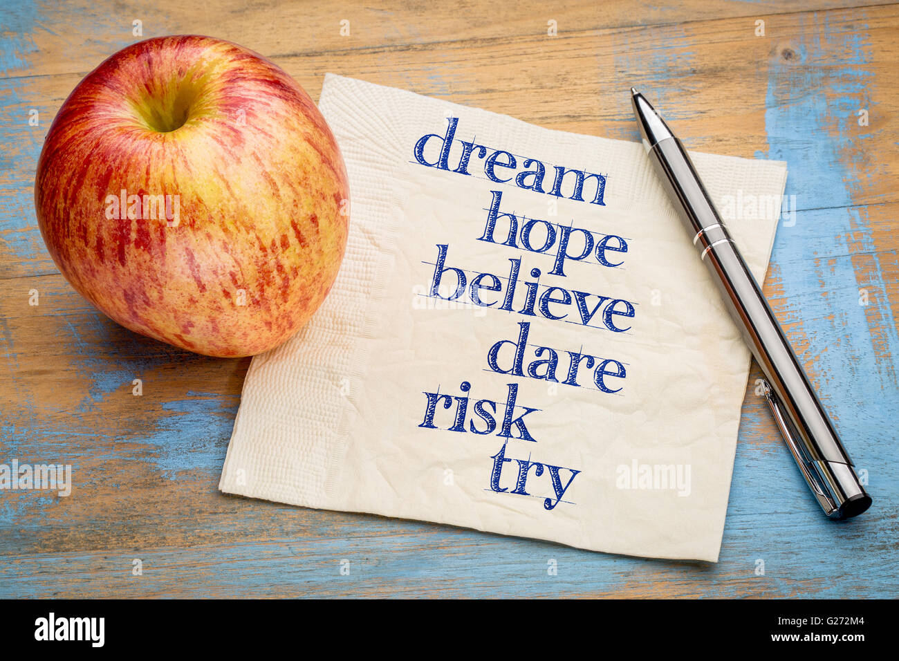 dream, hope, believe, dare, risk and try - handwriting on a napkin with a fresh apple Stock Photo