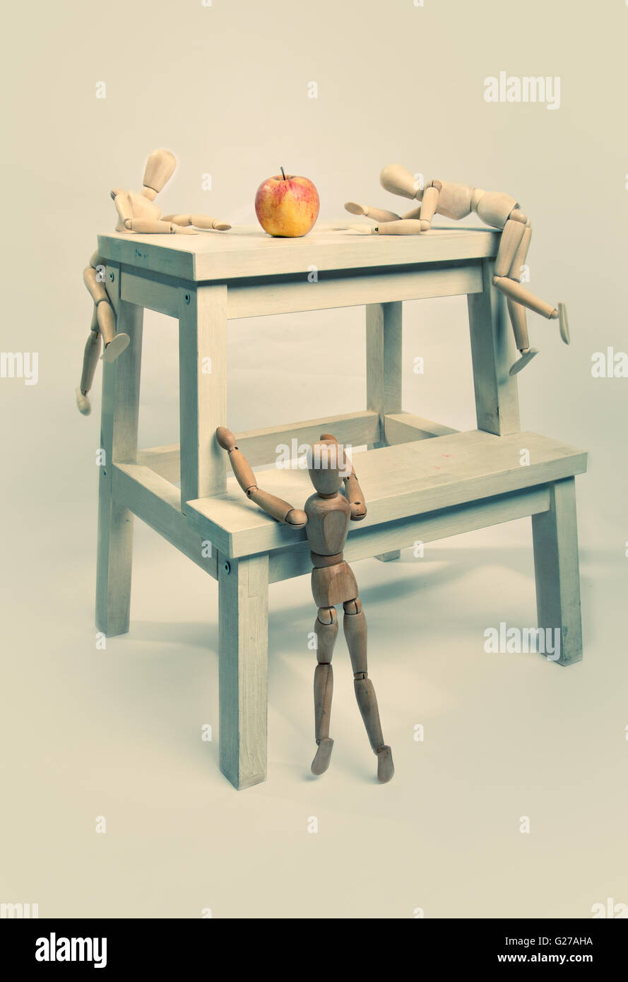 Three jointed dolls try to get to the apple first Stock Photo