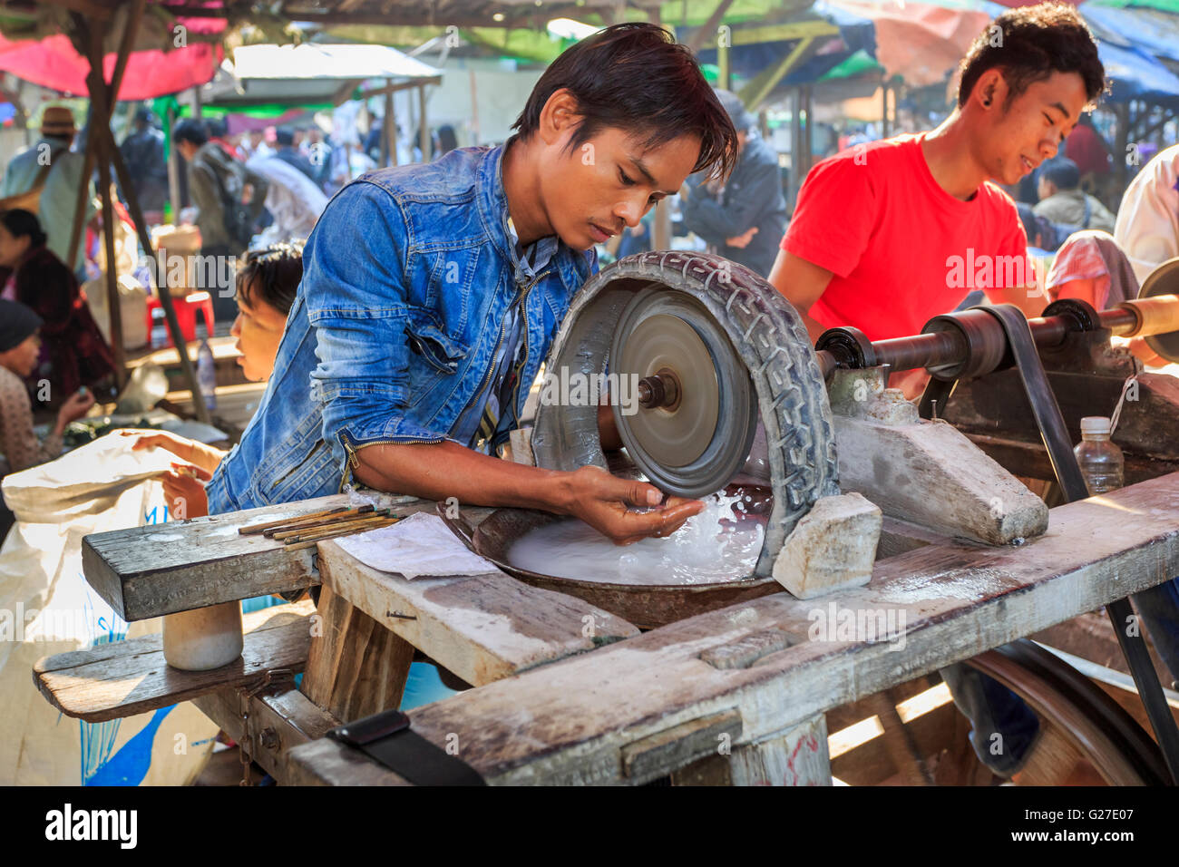 Young local craftsman working at polishing jade with a wheel in the