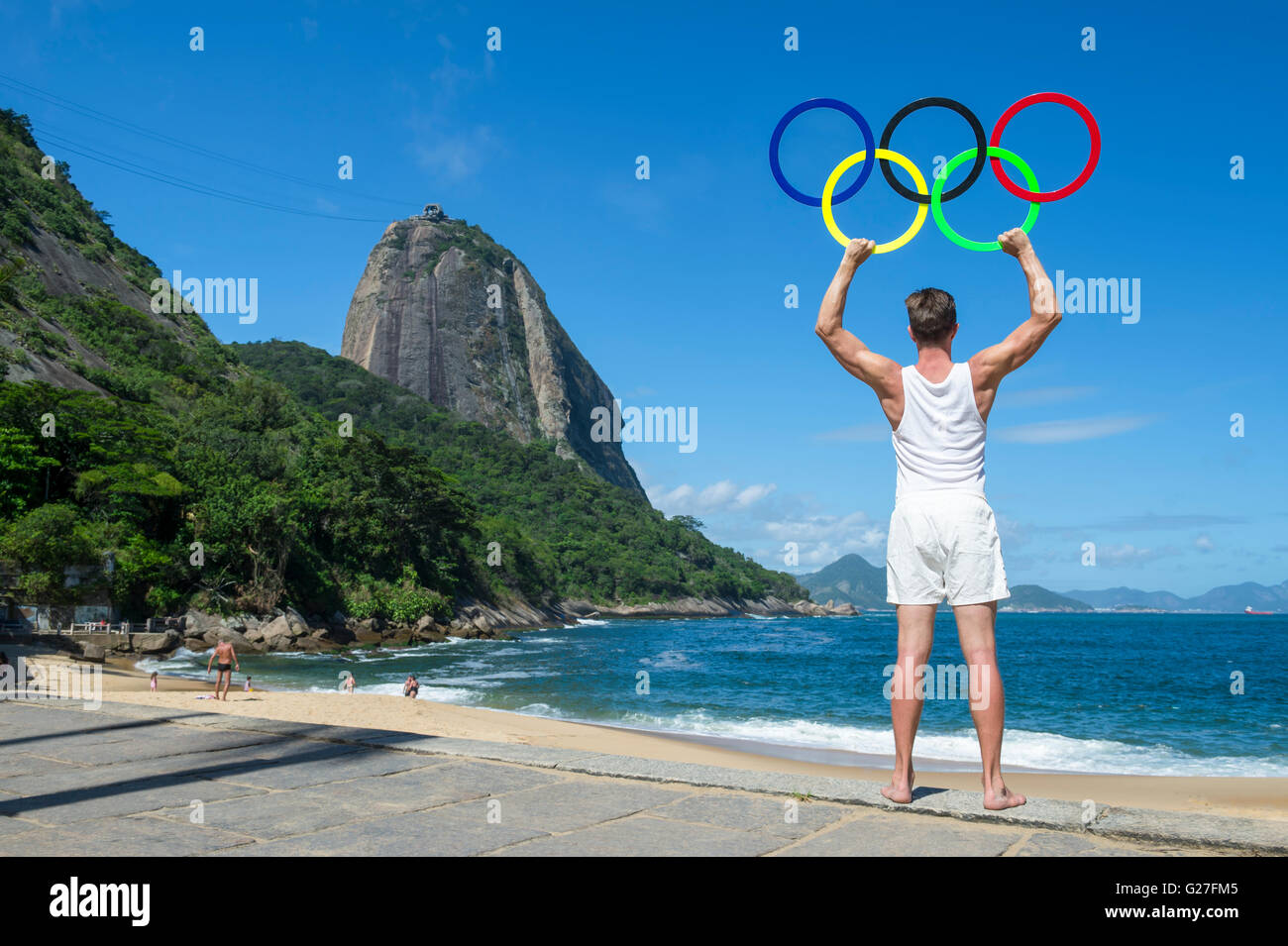RIO DE JANEIRO - APRIL 2, 2016: Athlete holds Olympic rings in front of a view of Sugarloaf Mountain for the Summer Games. Stock Photo