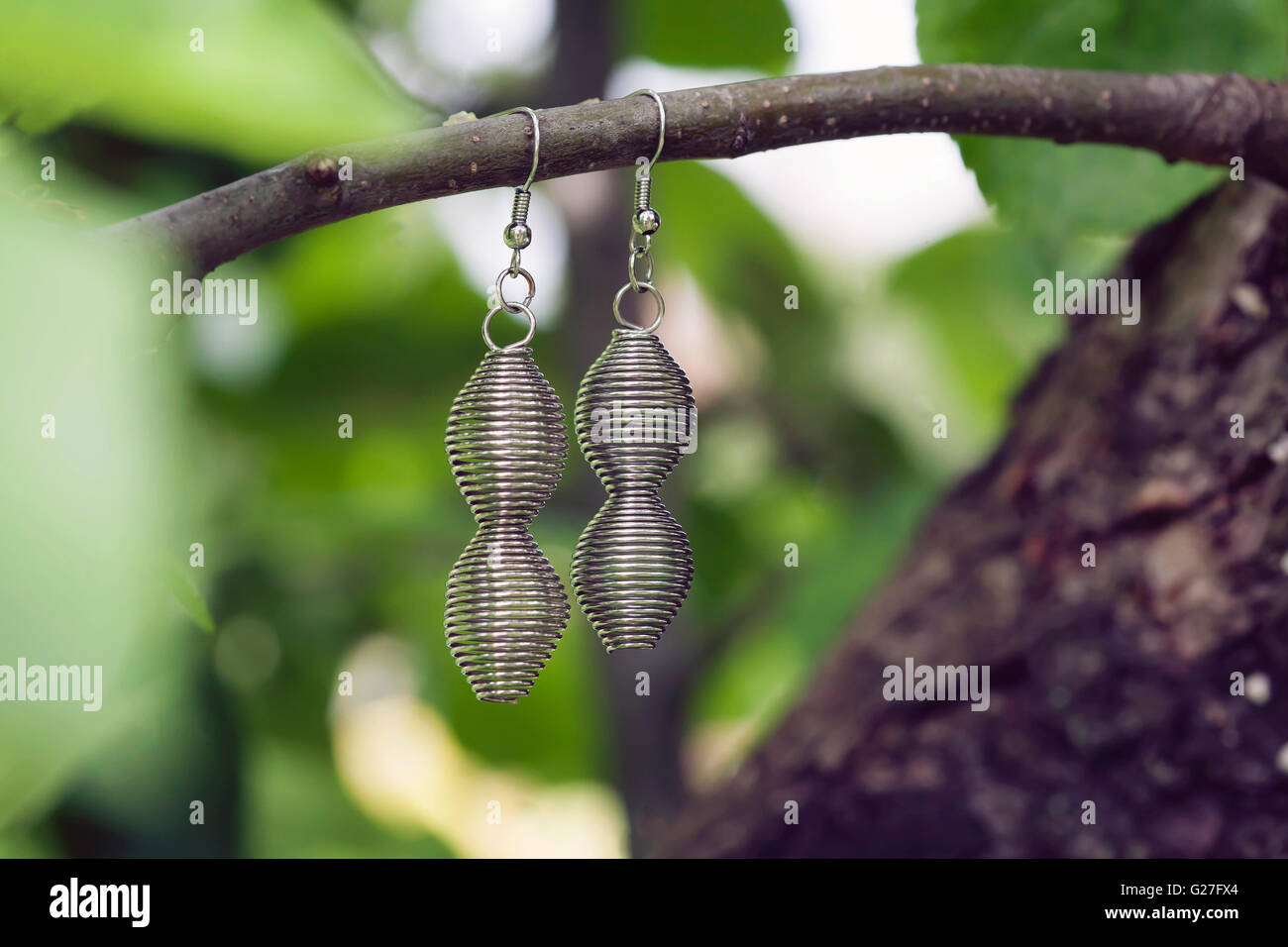 Spiral metal earring hanging on the branch Stock Photo