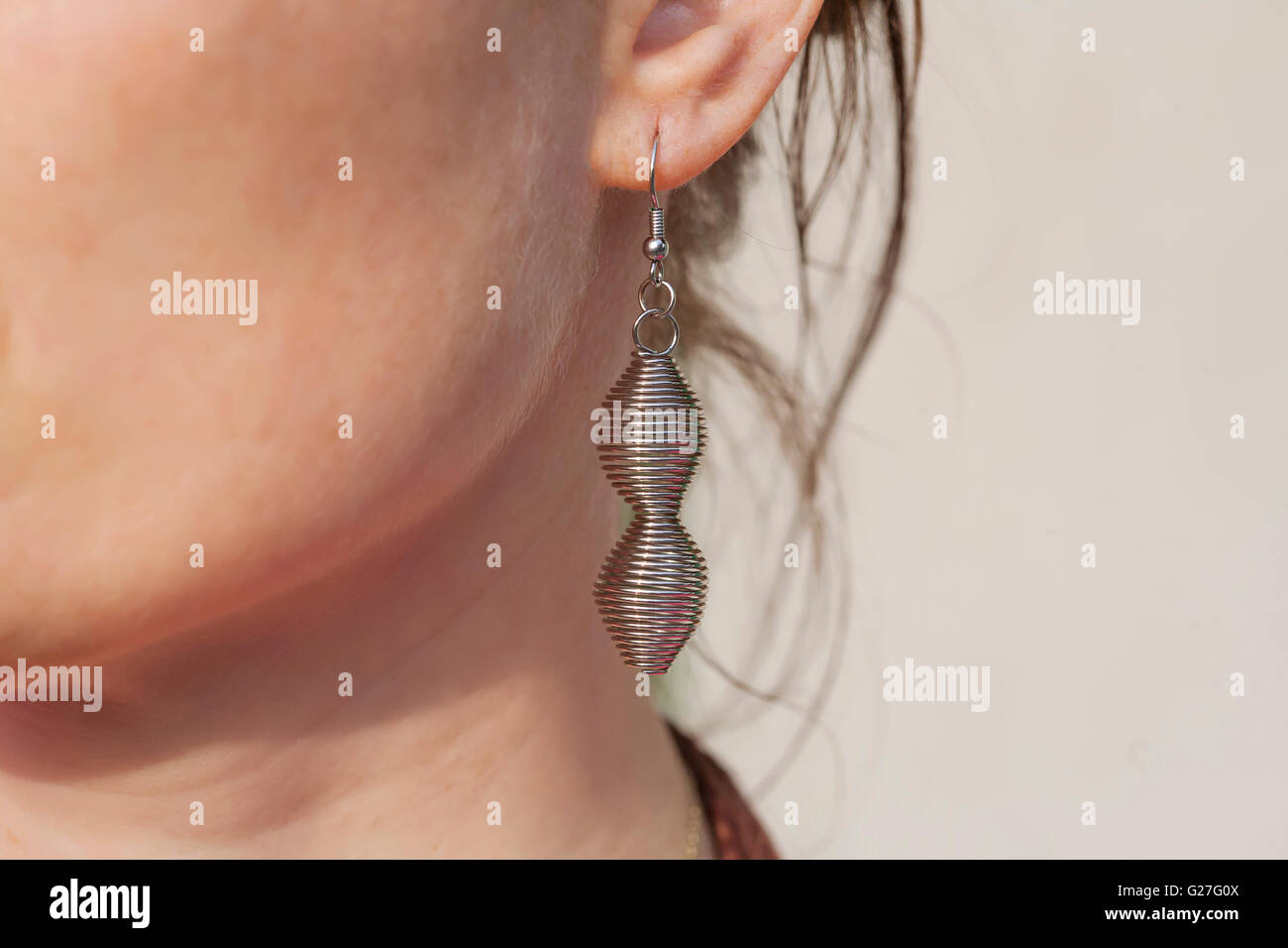 Spiral metal earring on female ear Stock Photo