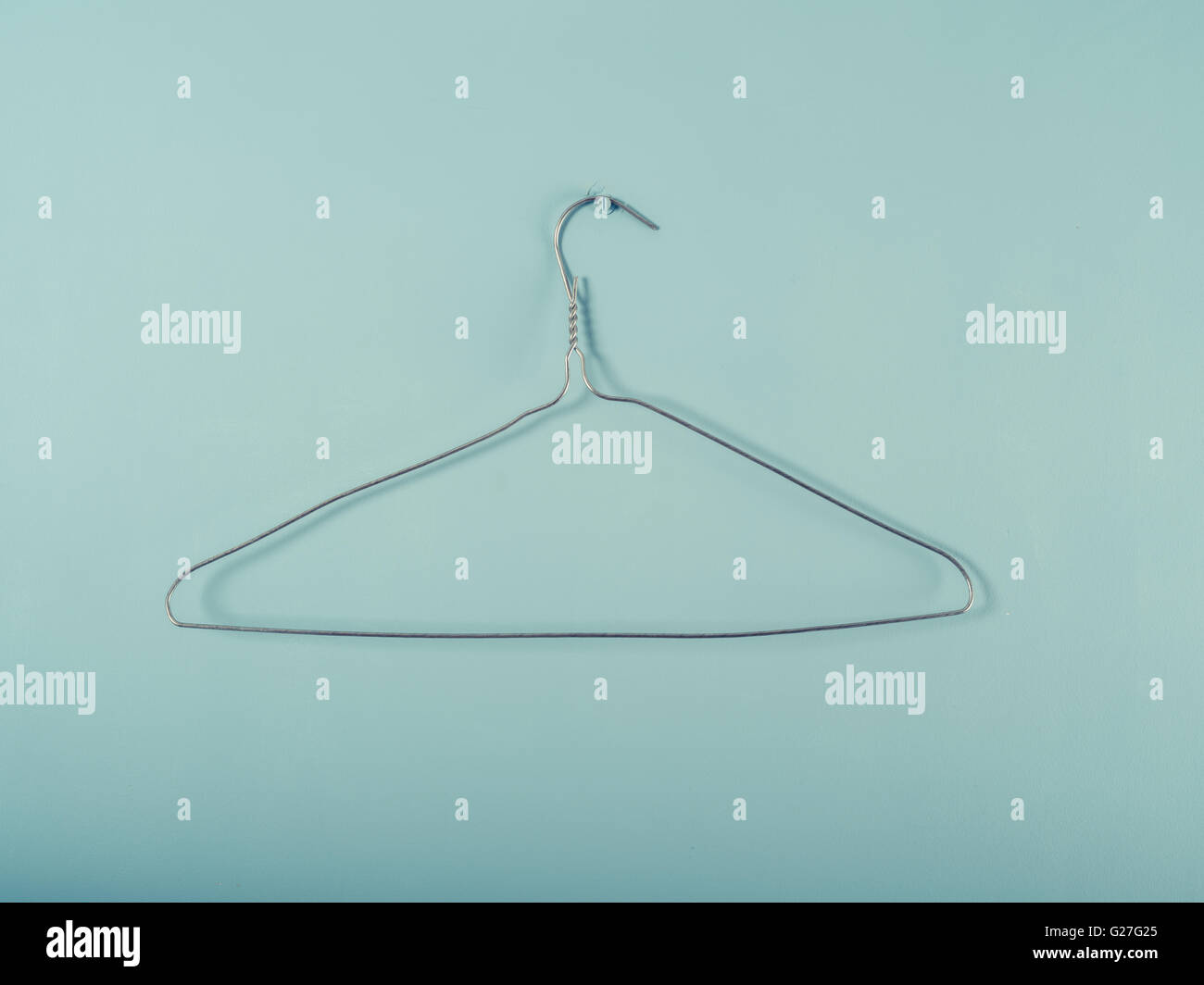 A wire hanger is hanging from a blue wall Stock Photo