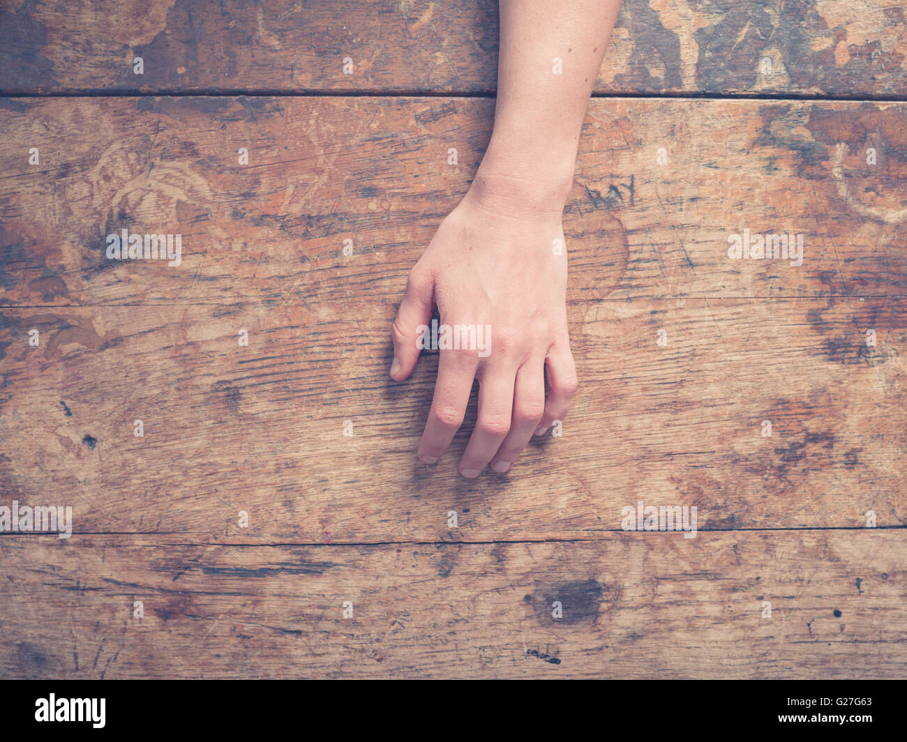 A young female hand on a wooden table Stock Photo