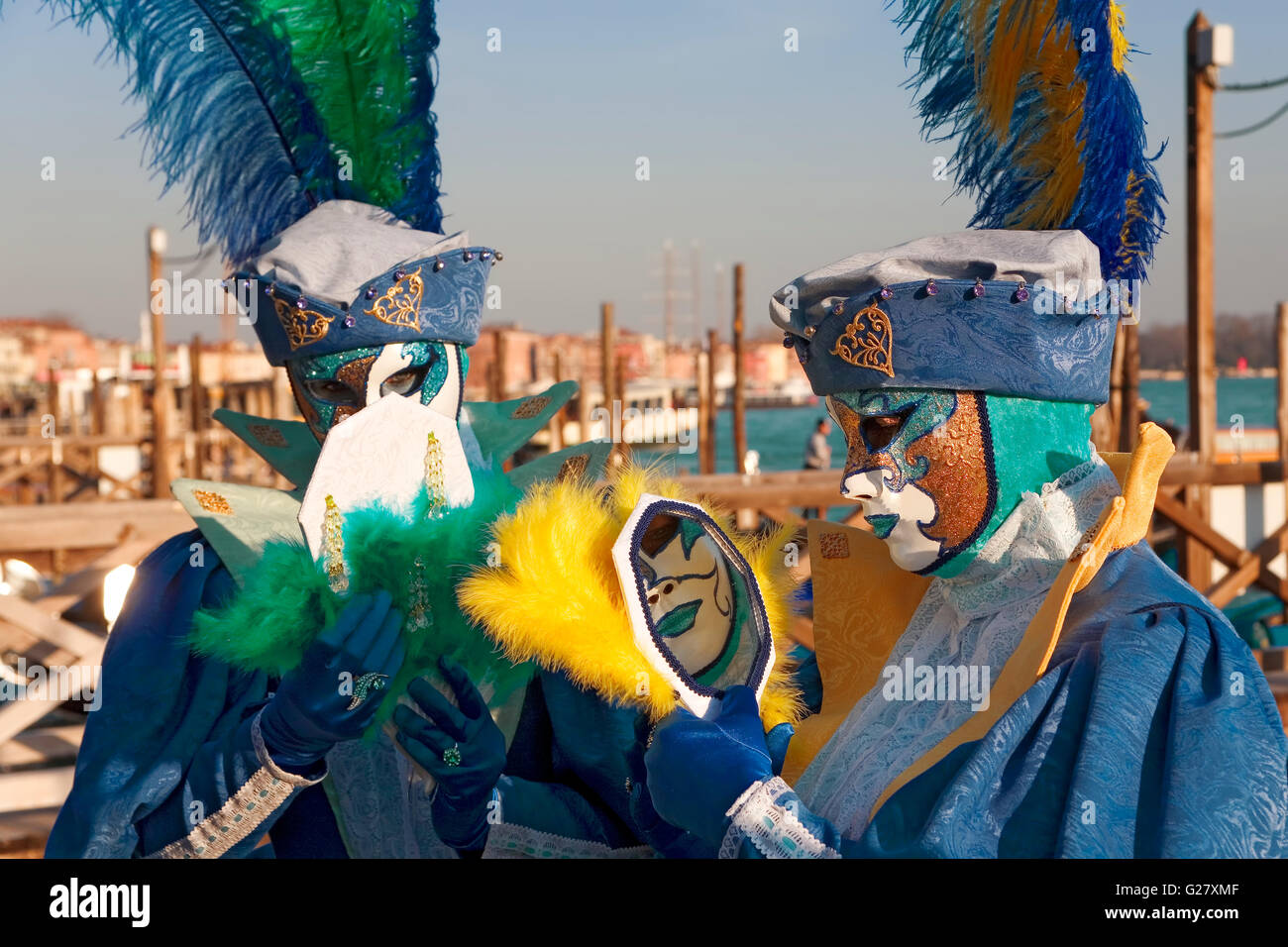 Molo San Marco, Venice, Italy: masked revellers pose in front of the Basin of St Mark, on a gondola landing stage Stock Photo