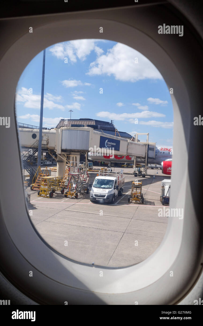 Looking through an aircraft window at a jet bridge or passenger boarding bridge at Manchester Airport England UK Stock Photo