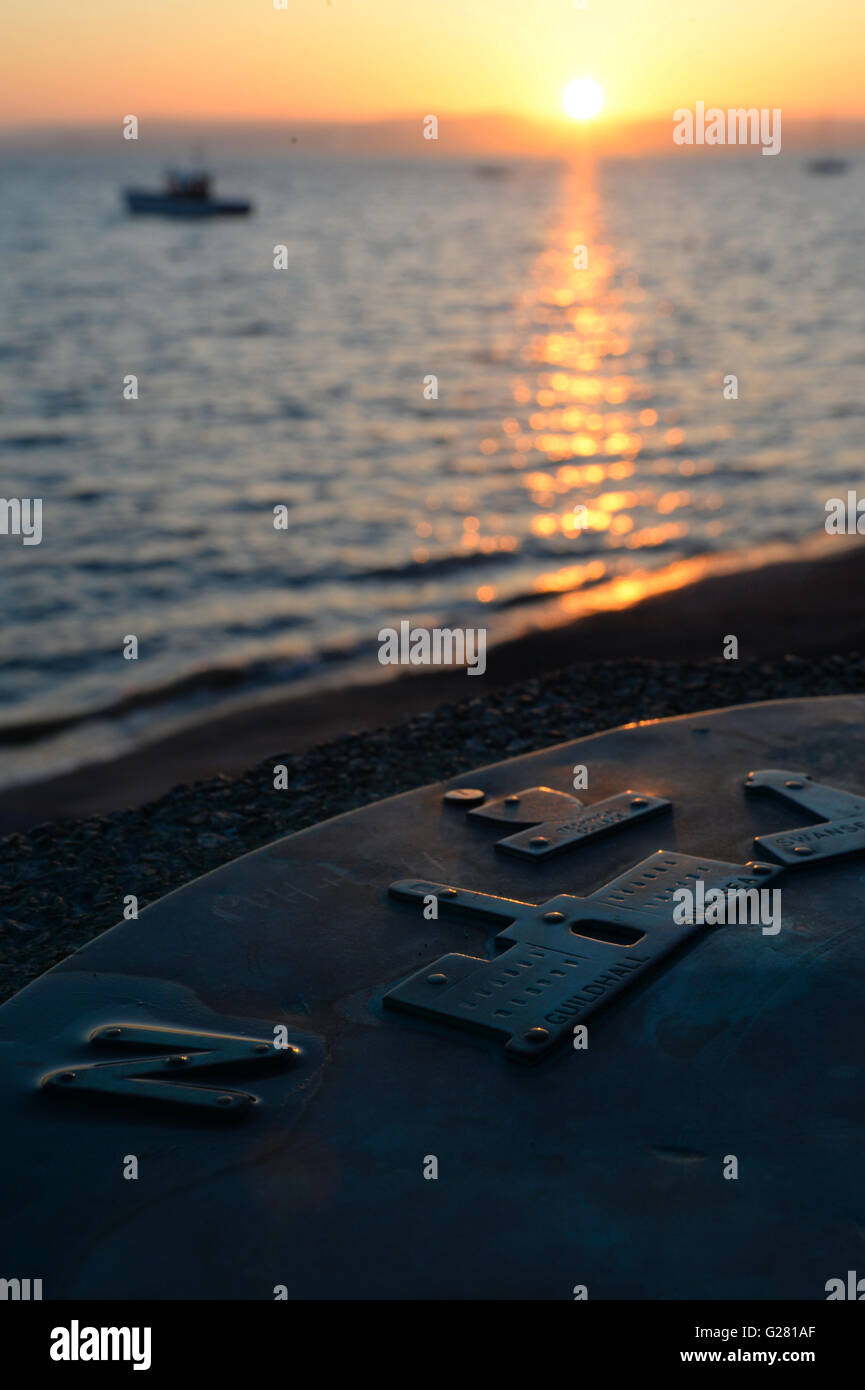 The rising sun reflected on the sea and a cast metal compass Stock Photo
