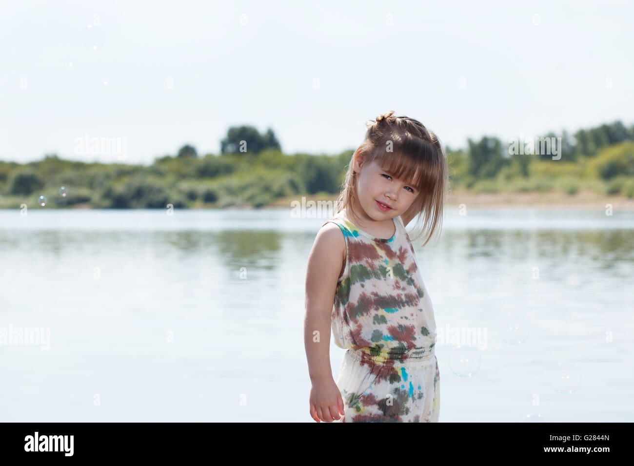 Smiling little girl posing by river Stock Photo - Alamy
