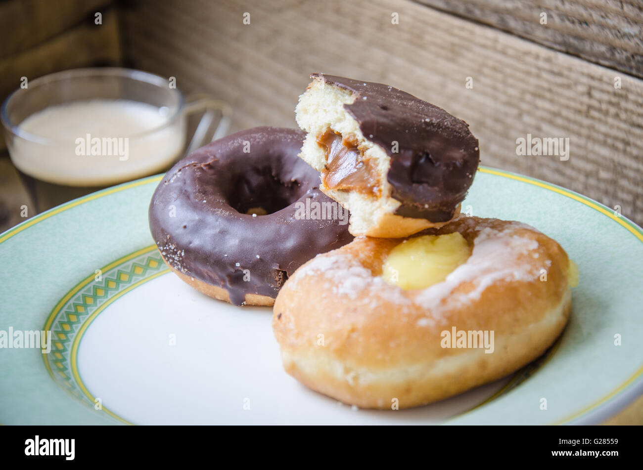 donut with bite in the foreground with black coffee and donuts background Stock Photo