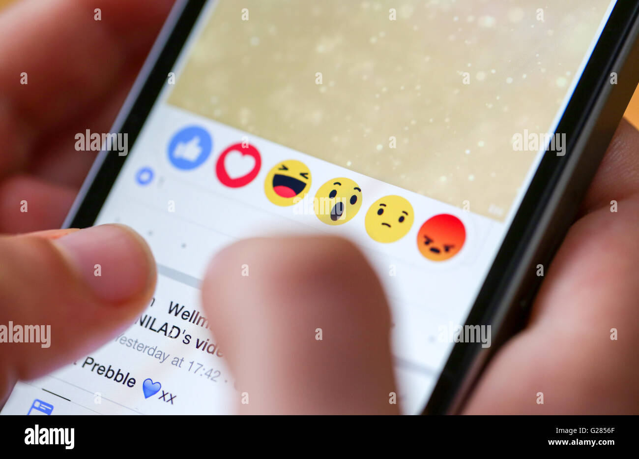 A teenager using reactions on the facebook app on a smart phone Stock Photo