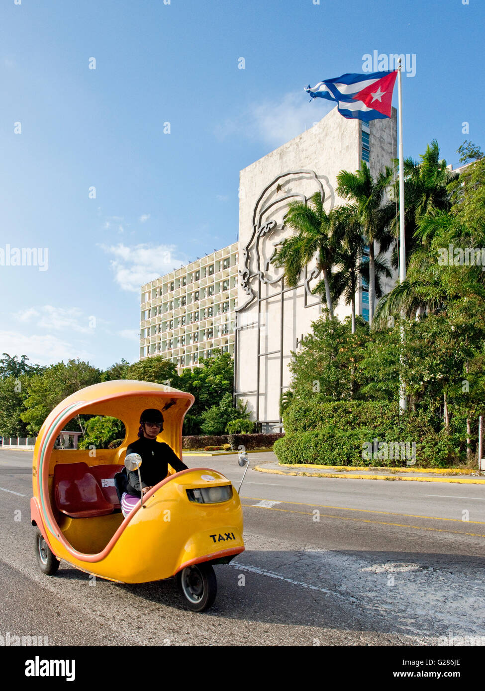 A coco taxi driving past the Ministry of Interior building on Revolution Square with the image of Che Guevara in the background. Stock Photo
