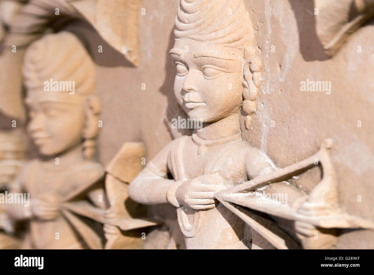 Stone Indian carving of a human figure holding a bow and arrow. Stock Photo