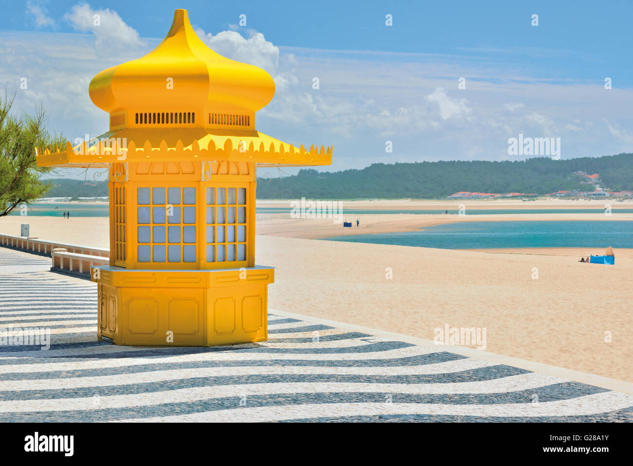 Portugal: Yellow kiosk and decorated portuguese cobblestone sidewalk with sand and lagoon Lagoa de Obidos in Foz do Arelho Stock Photo