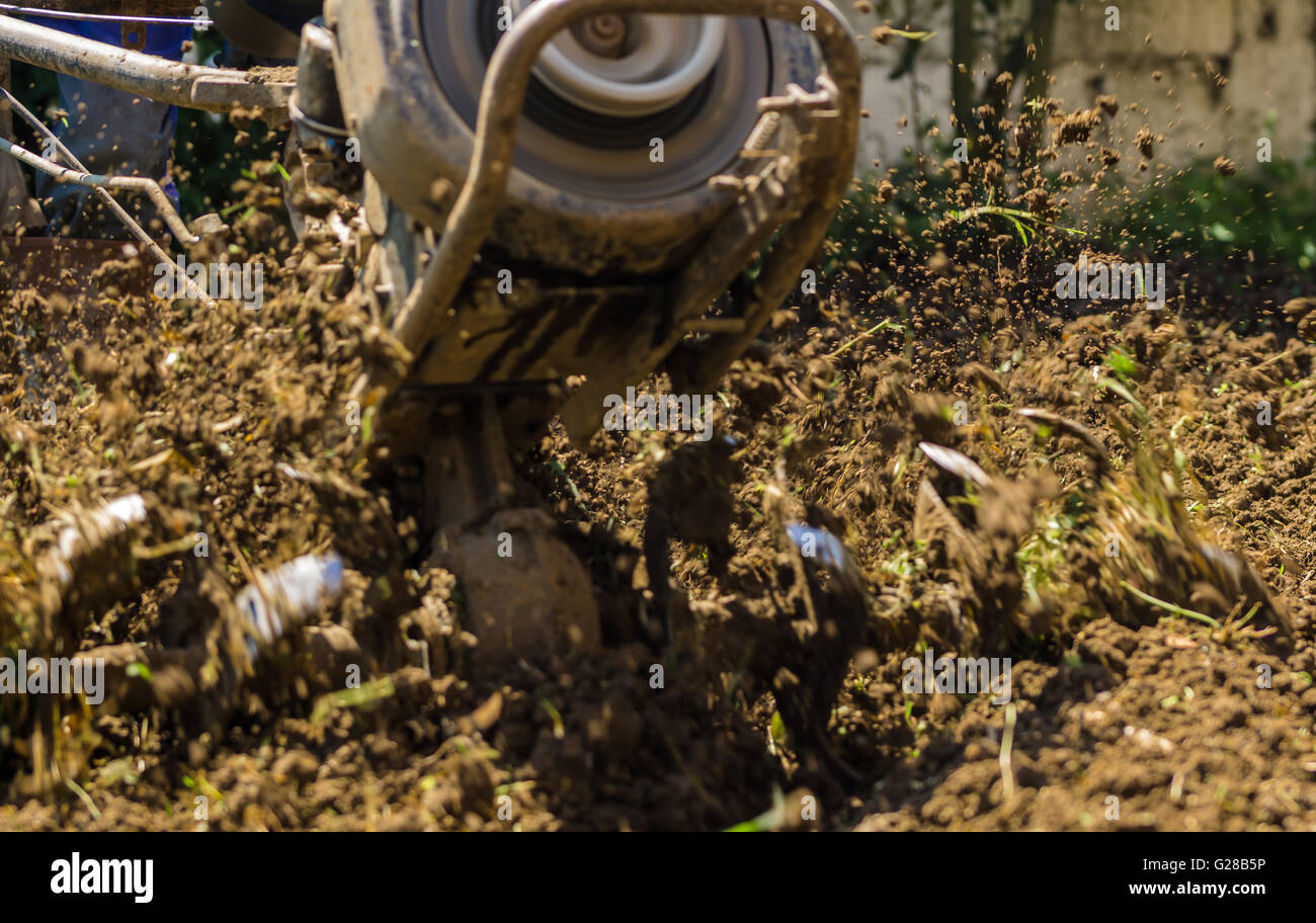 Farmer using machine mart cultivator for ploughing soil Stock Photo