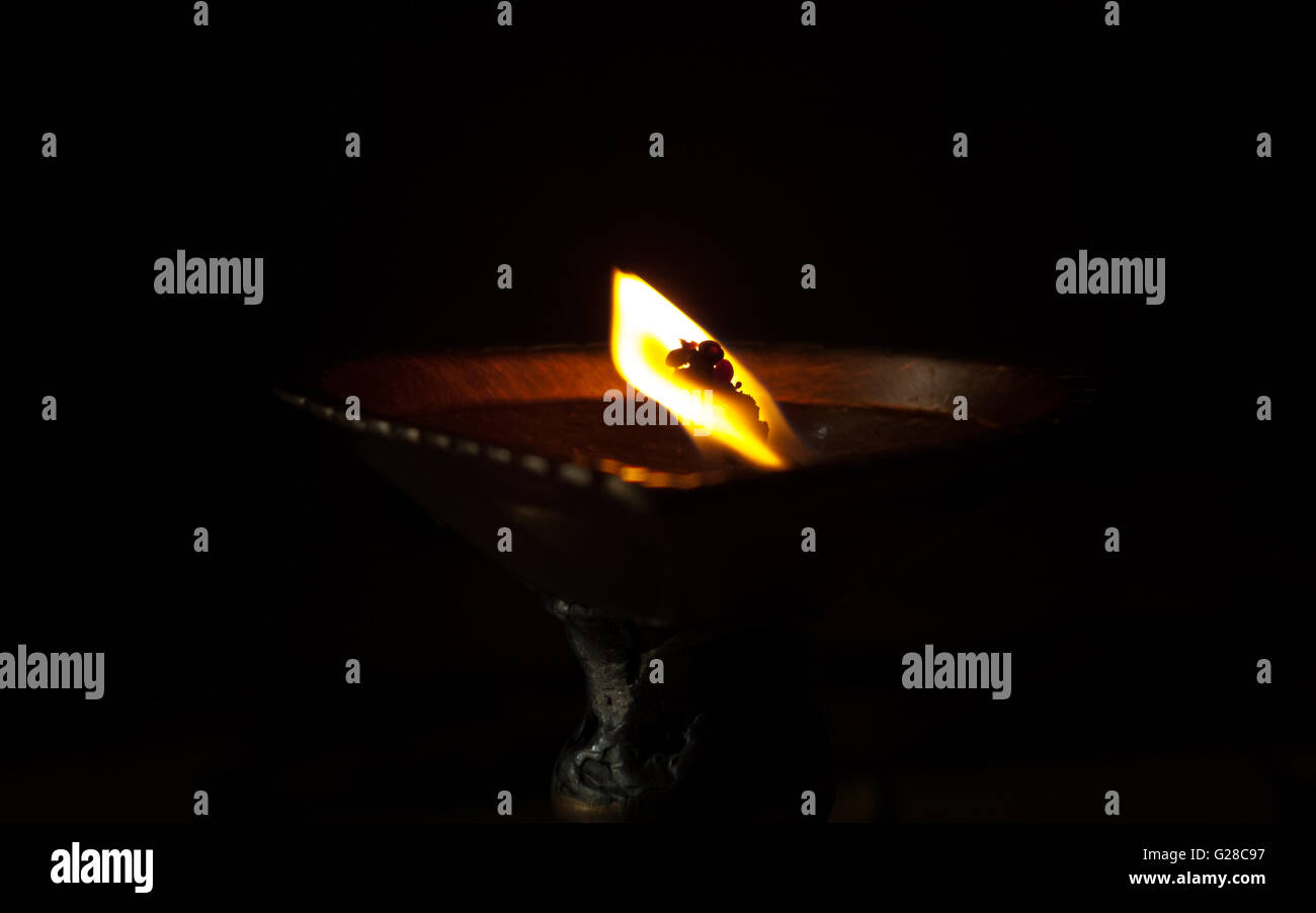 flame from oil lamp dark background deformed wick in hindu temple prayer ritual Stock Photo