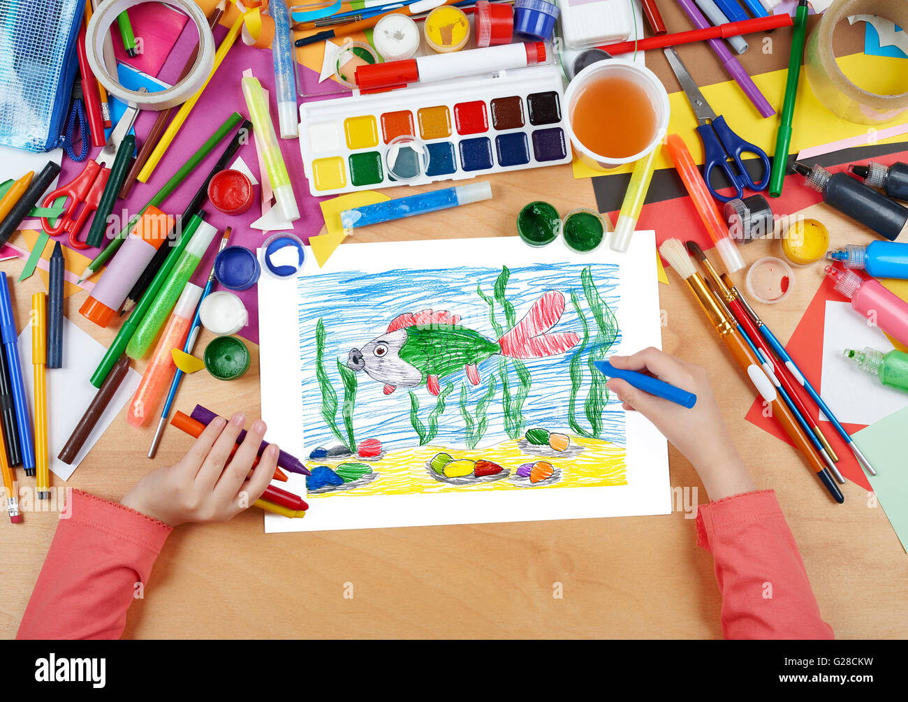 big fish under water child drawing, top view hands with pencil painting picture on paper, artwork workplace Stock Photo