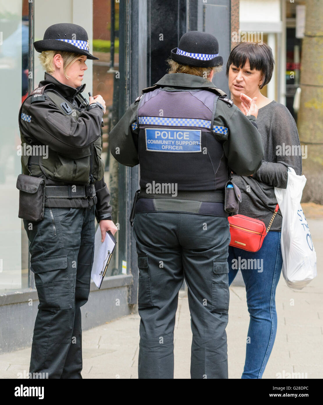 Police community support officers speaking to a pedestrian in a town in the UK. Stock Photo