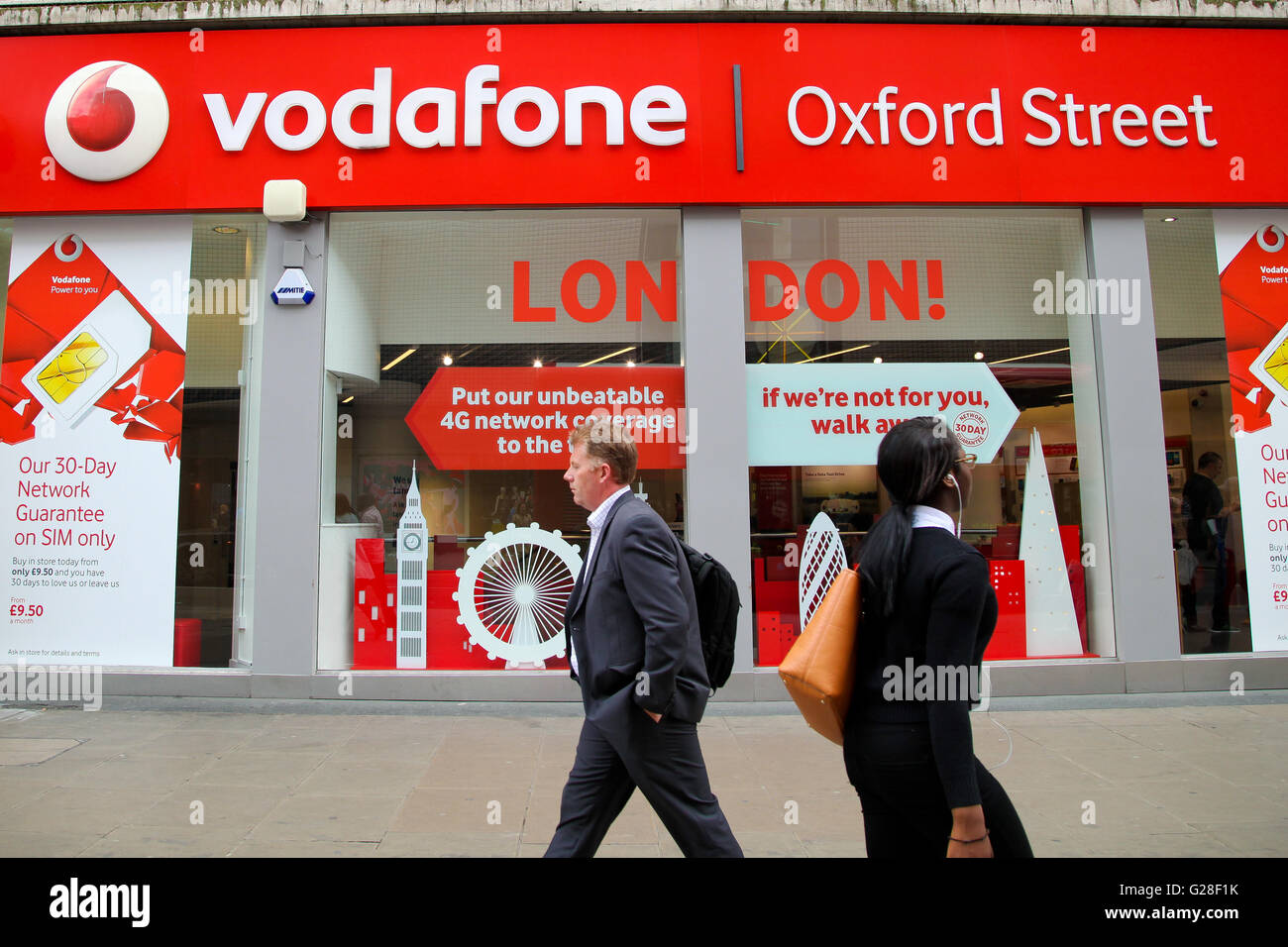 People pass by the Vodafone mobile phone store in Oxford Street in