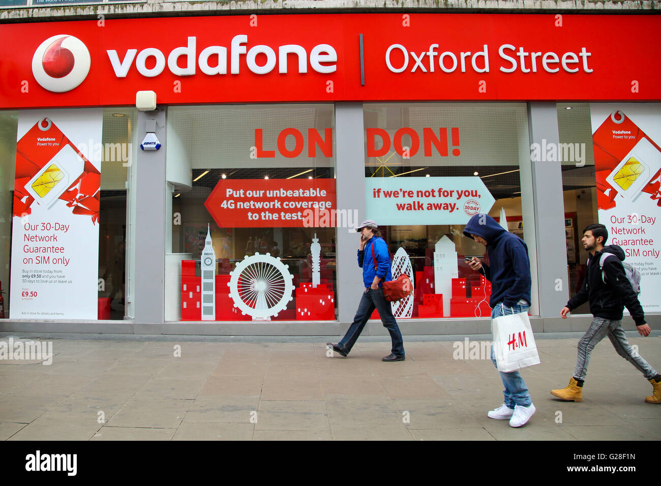 People pass by the Vodafone mobile phone store in Oxford Street in London Stock Photo