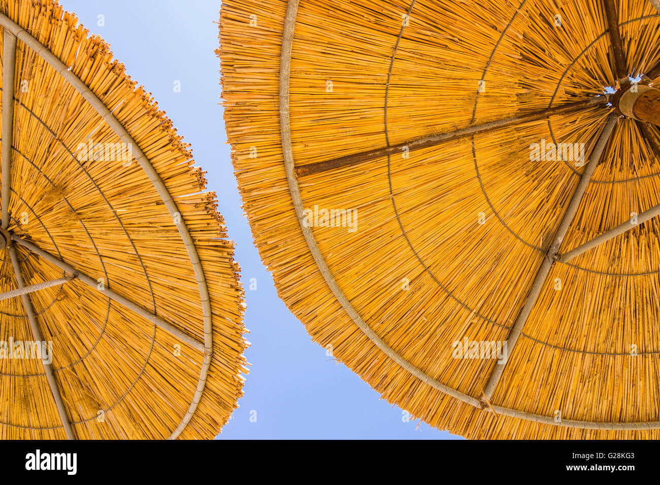 Detail of two bamboo sun umbrellas against a blue sky Stock Photo