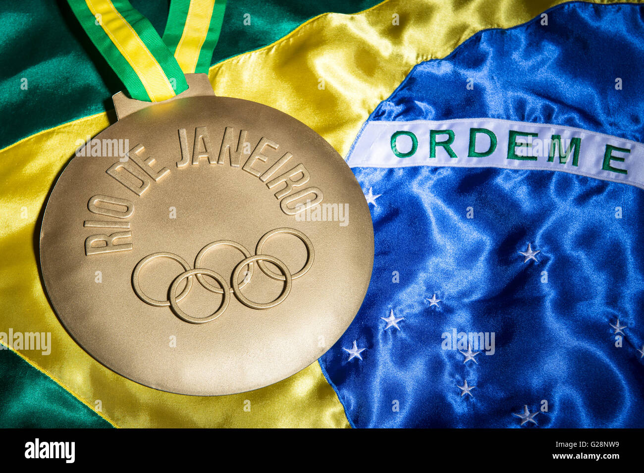 RIO DE JANEIRO - FEBRUARY 3, 2015: Large gold medal commemorating the 2016 Olympic Games sits on Brazil flag background. Stock Photo