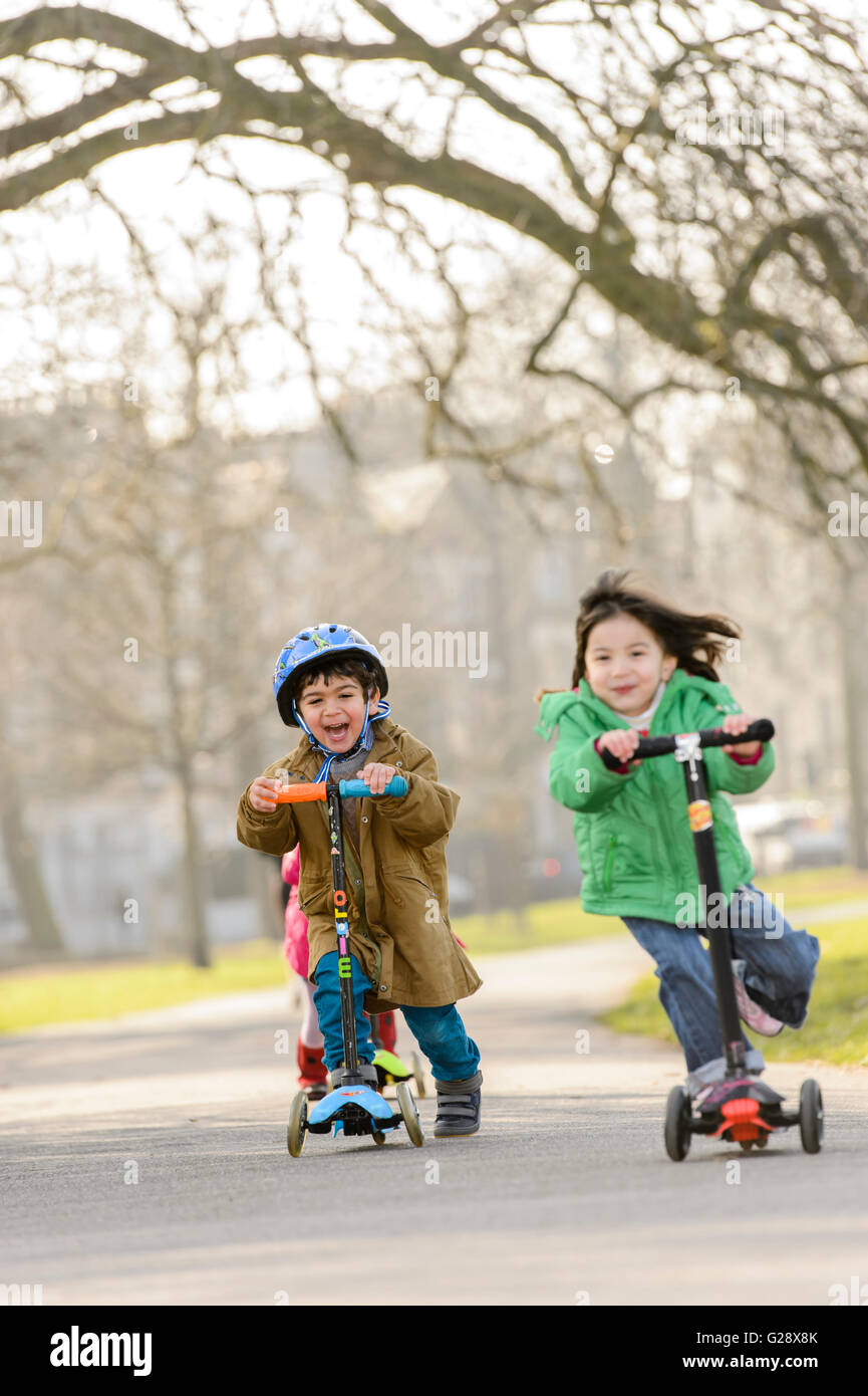 Kids playing with kickboards in a park Stock Photo - Alamy