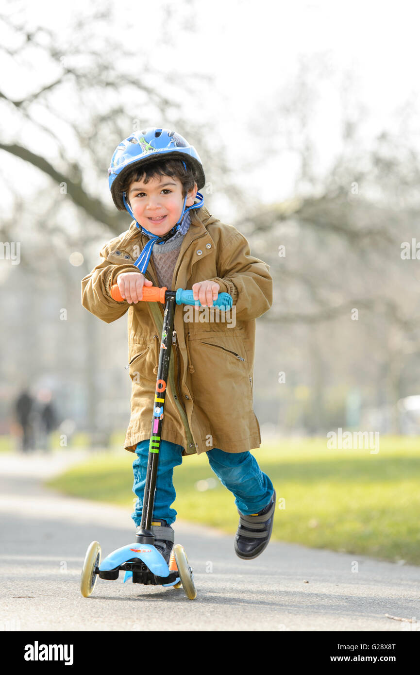 Kid playing with kickboard in a park Stock Photo - Alamy