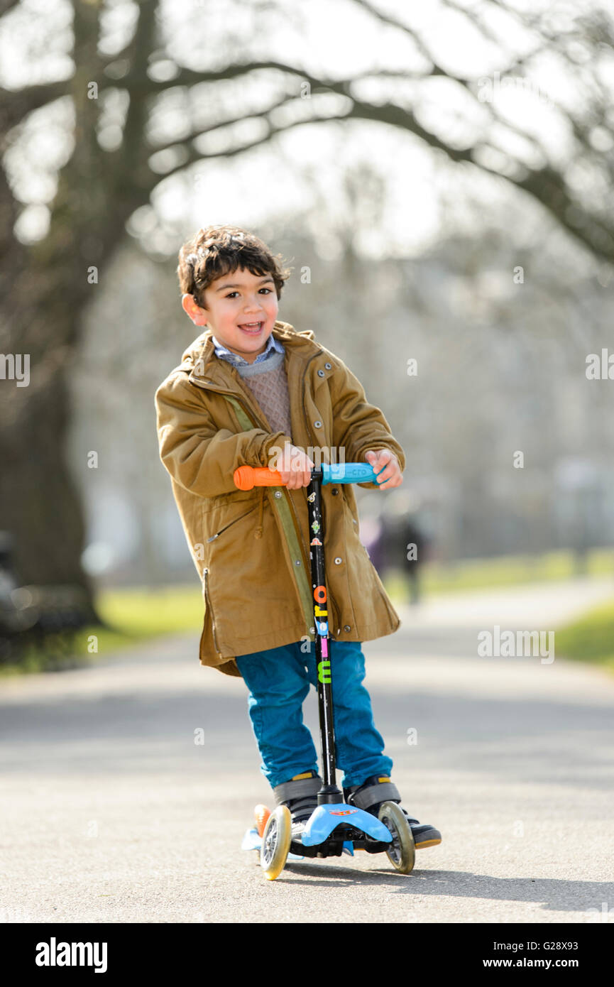 Kid playing with kickboard in a park Stock Photo - Alamy