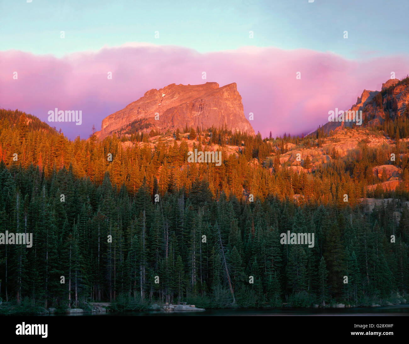 USA, Colorado, Rocky Mountain National Park, Sunrise reddens Hallett Peak and clouds above Bear Lake. Stock Photo