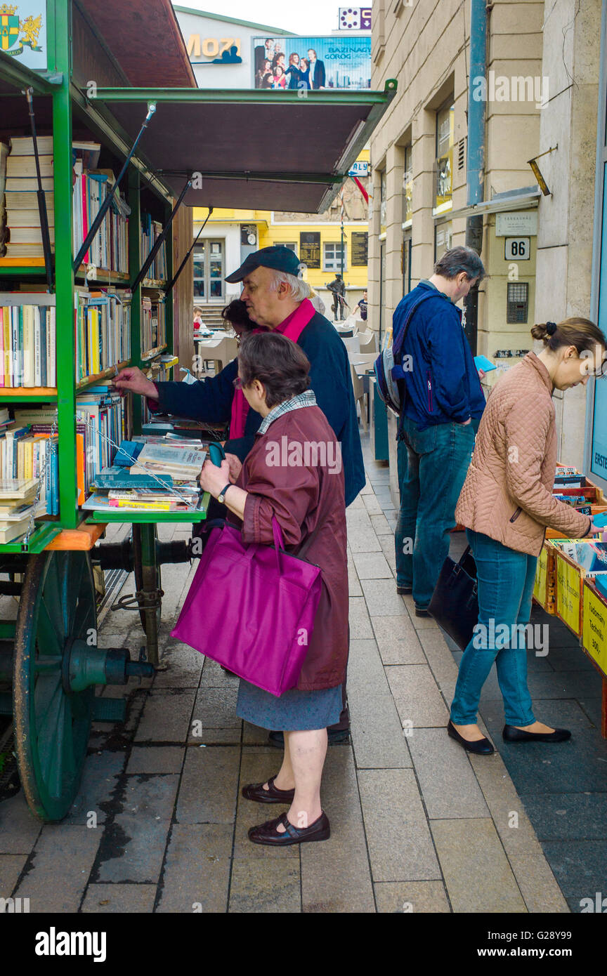 People study the titles of the books on a book cart in Corvin köz, Budapest. Stock Photo