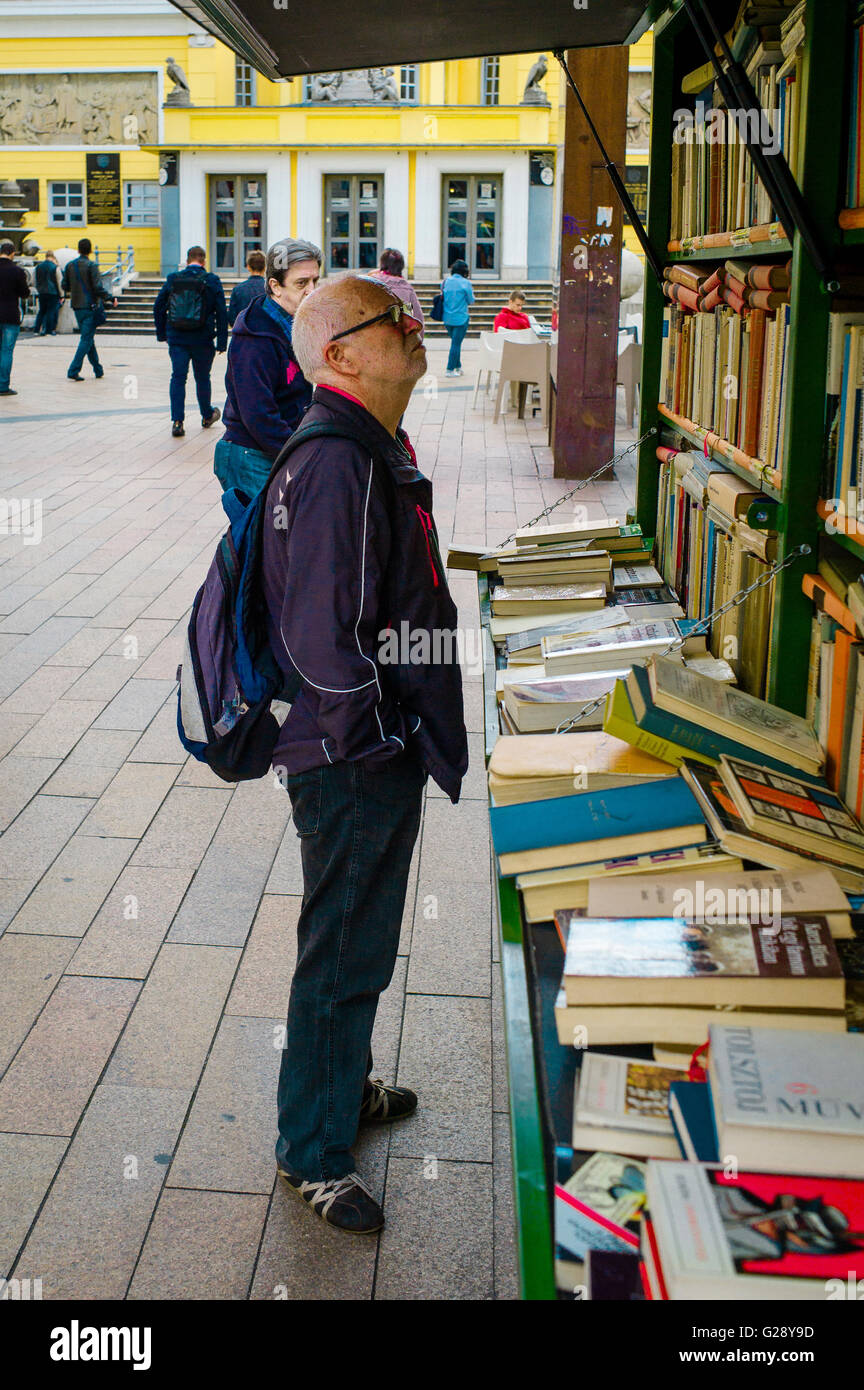 A man studies the titles of the books on a book cart in Corvin köz, Budapest. Stock Photo