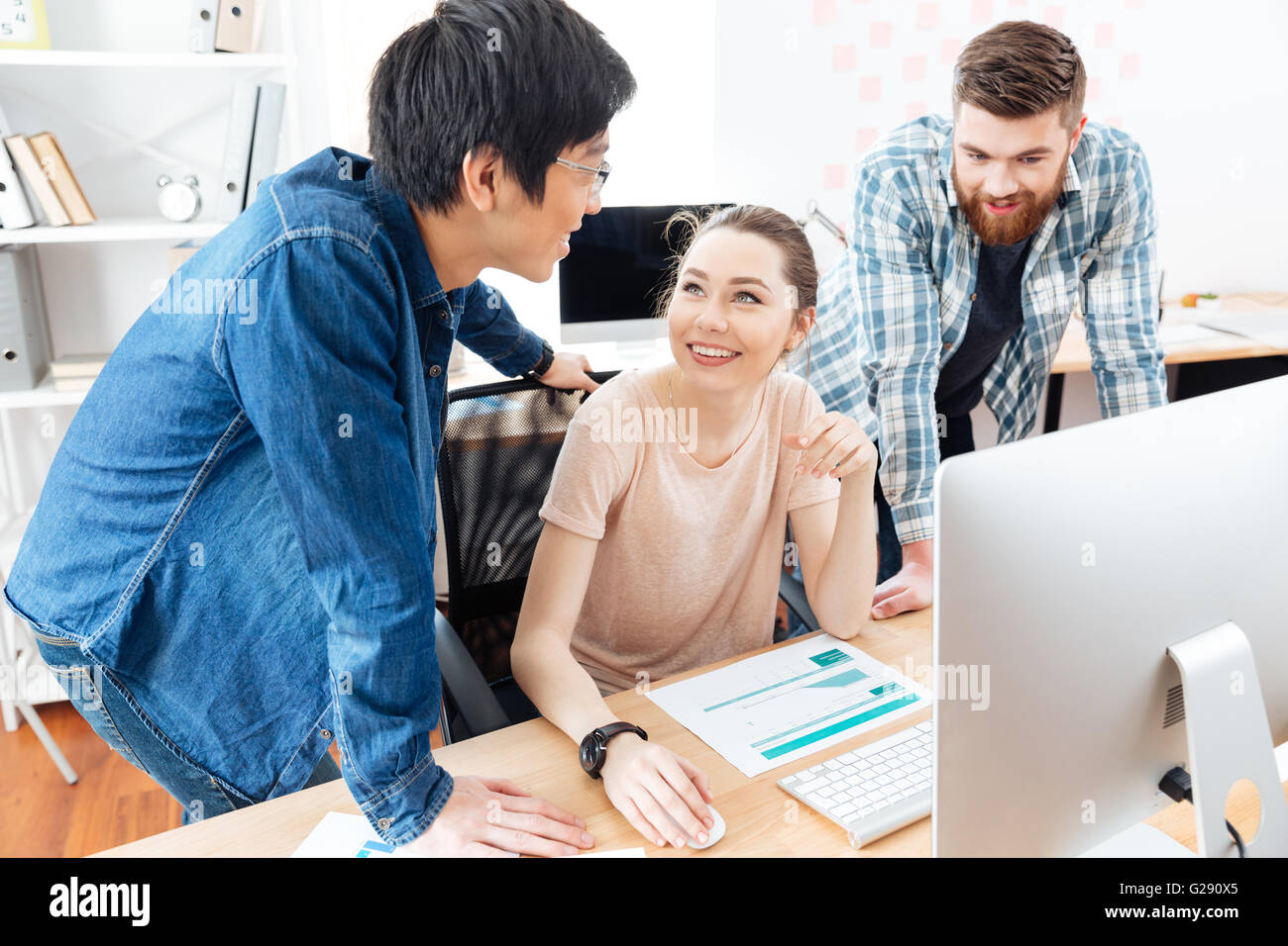 Three cheerful young businesspeople working in office together Stock Photo