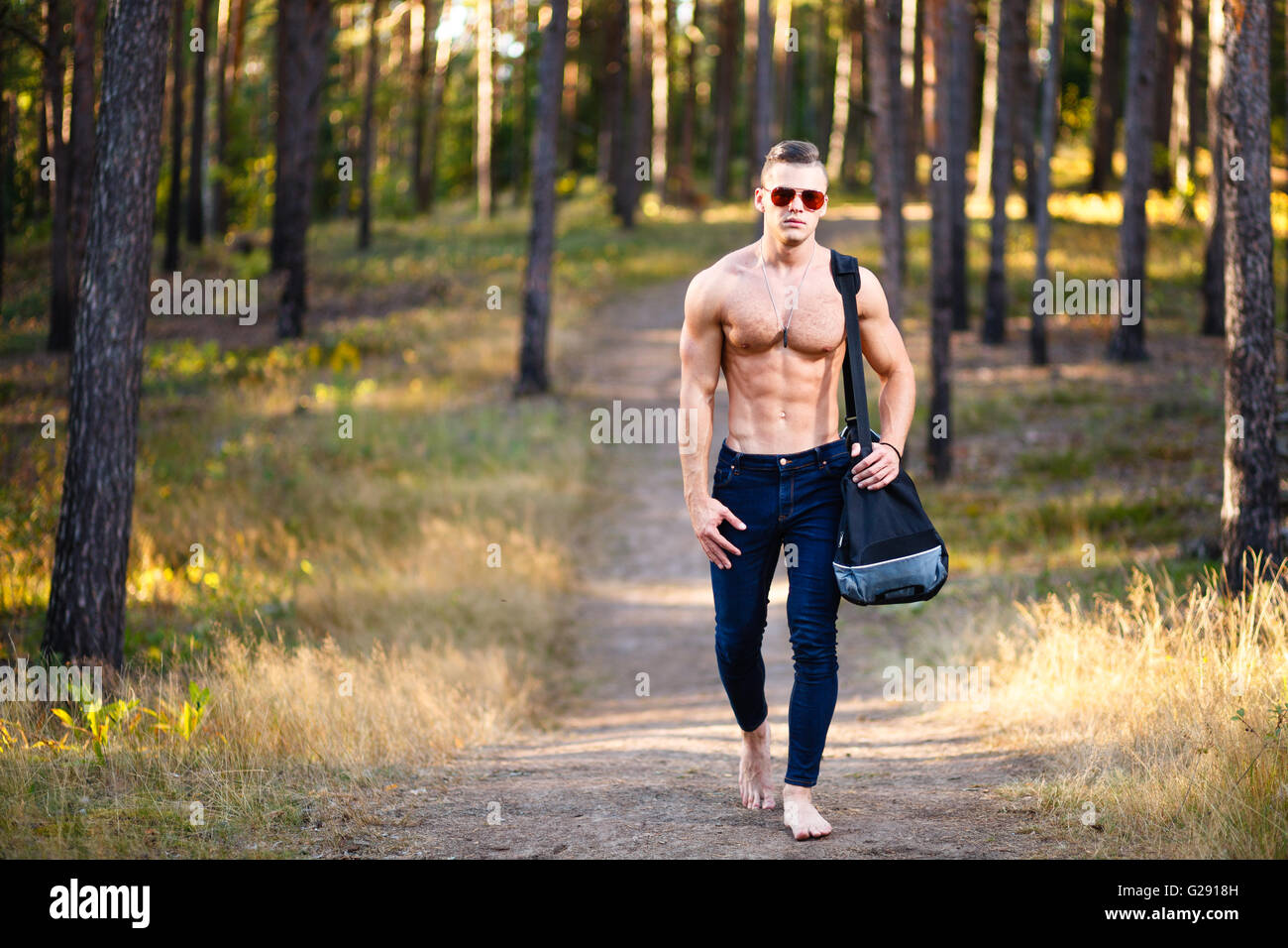 Muscular young man with bag in a forest. Stock Photo