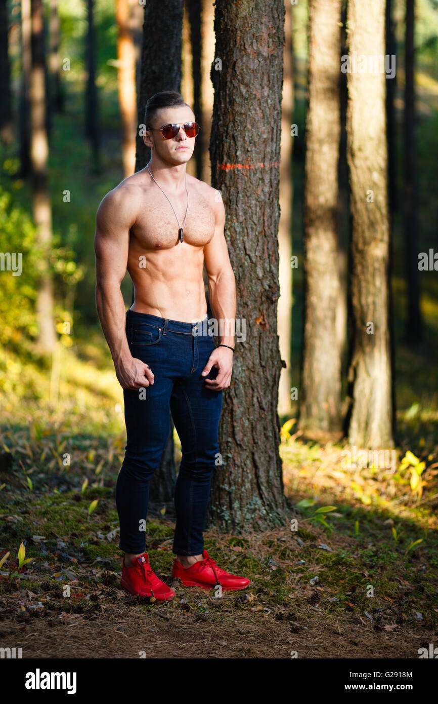 Muscular young man with sunglasses in a forest. Stock Photo