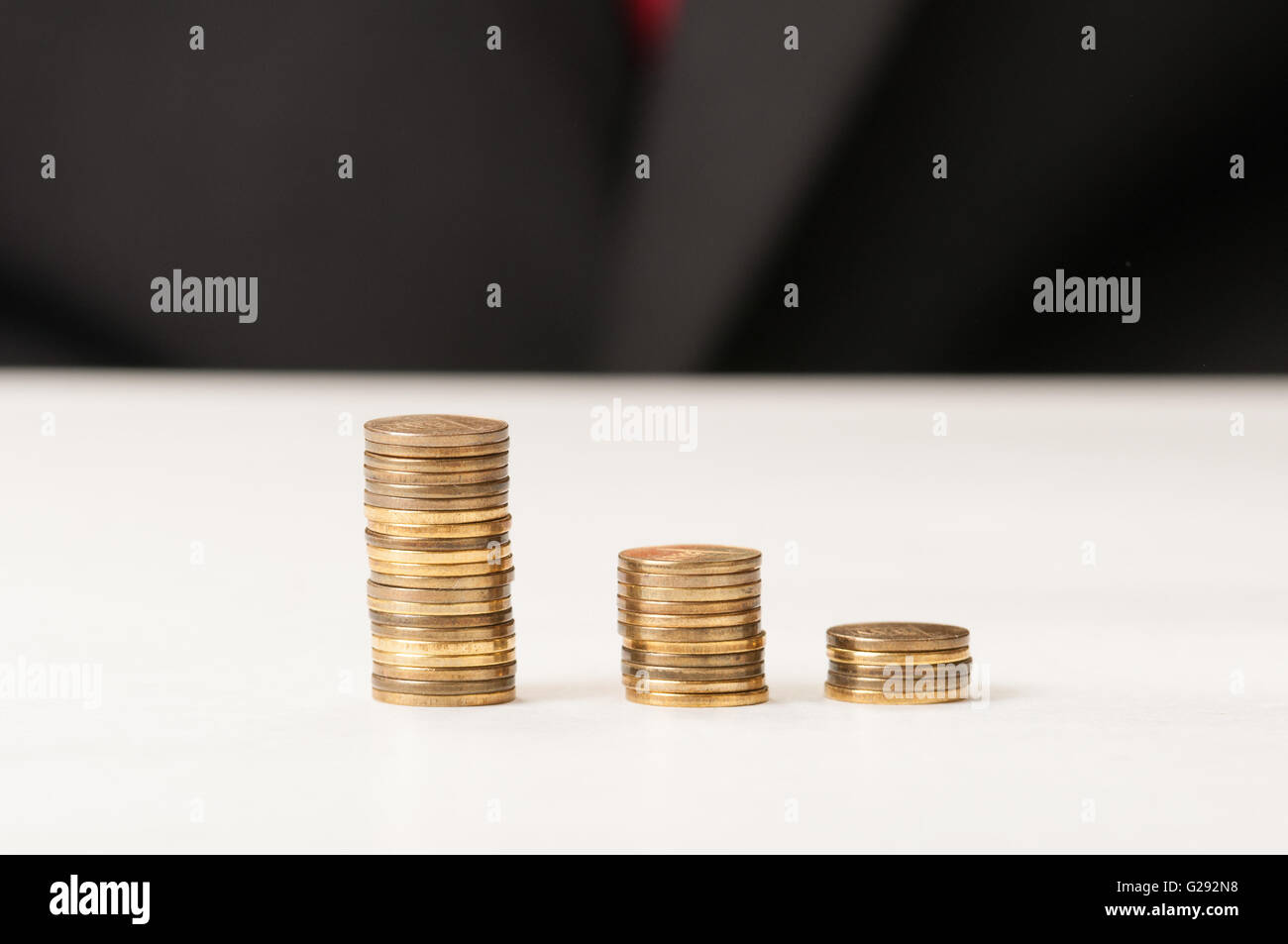 Three piles of golden coins on the table decreasing Stock Photo - Alamy