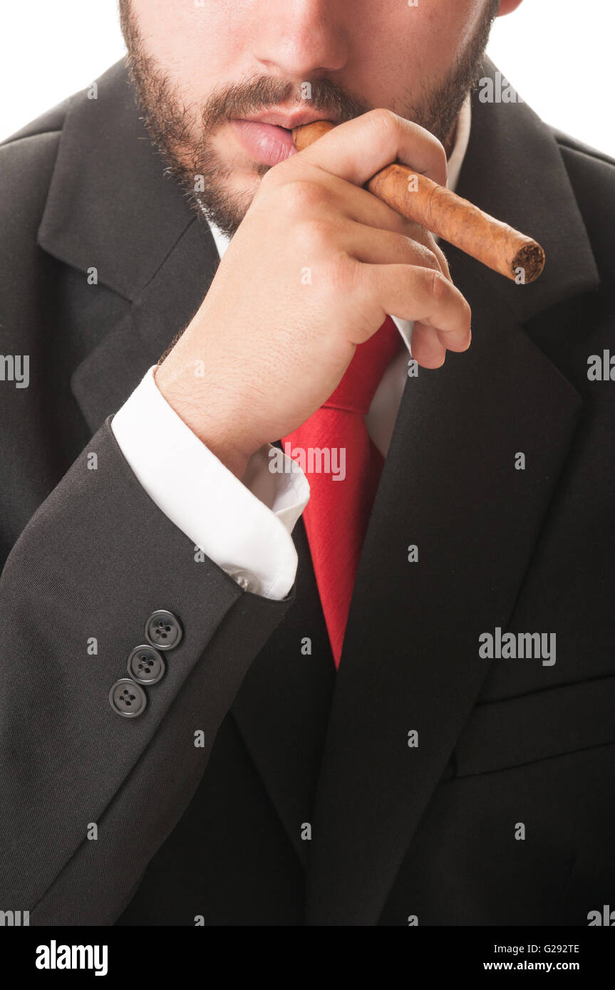 Sales agent smoking a cuban cigar. He wears a clasic black suit and red tie  Stock Photo