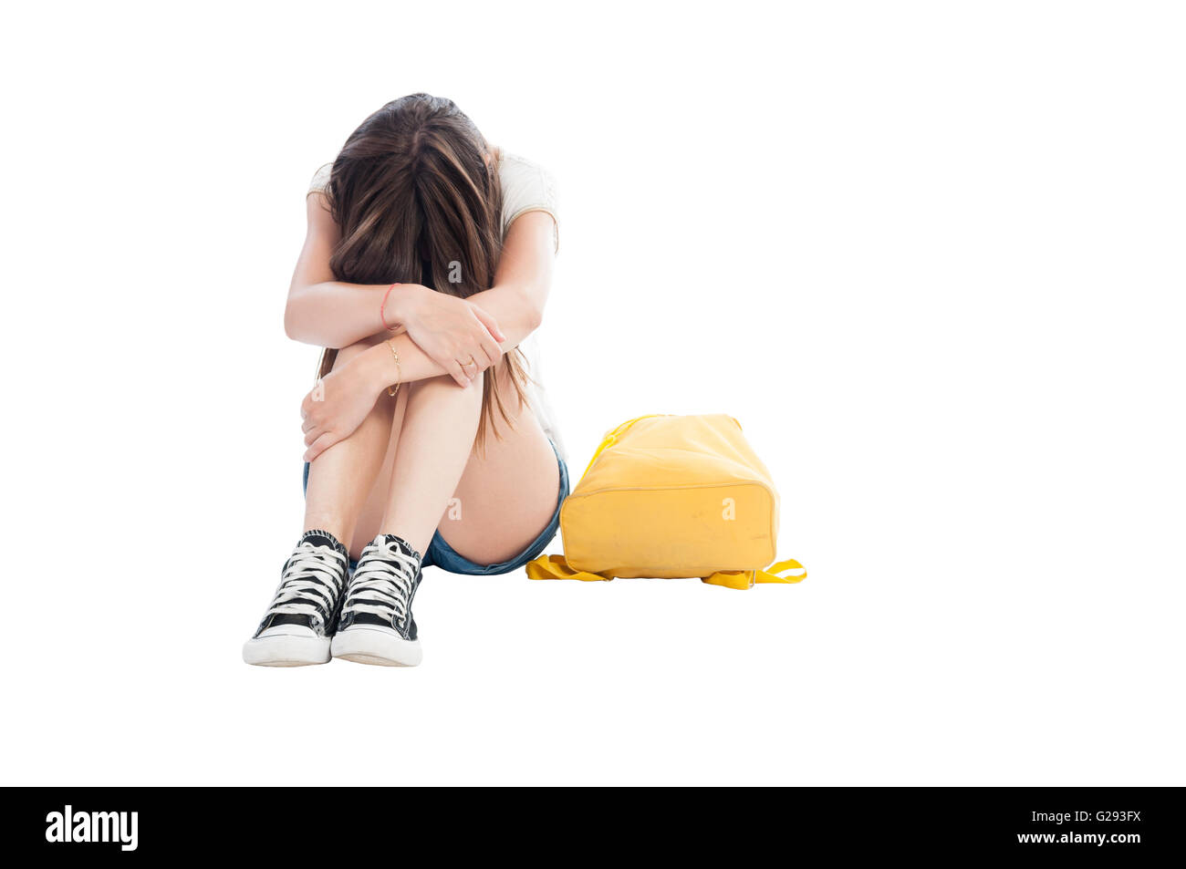 Upset girl holding her head on knees on white background Stock Photo