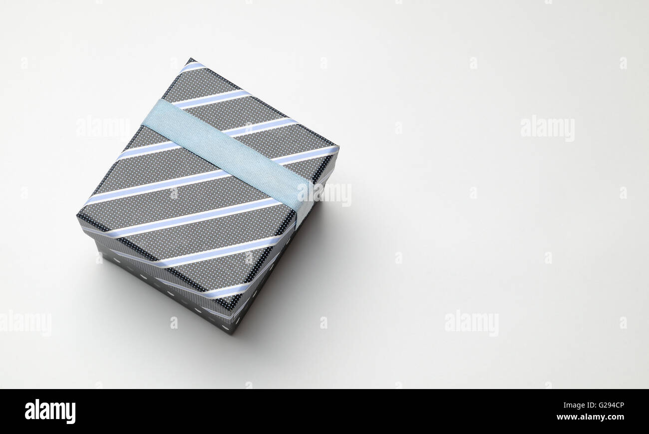 Decorative black gift box with with ribbon and blue diagonal lines painted with dots. Top perspective view. White isolated Stock Photo