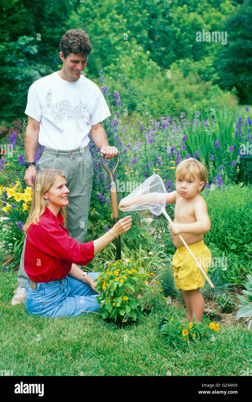 Family and young boy in garden with butterfly net makes a face at camera, Missouri, USA Stock Photo