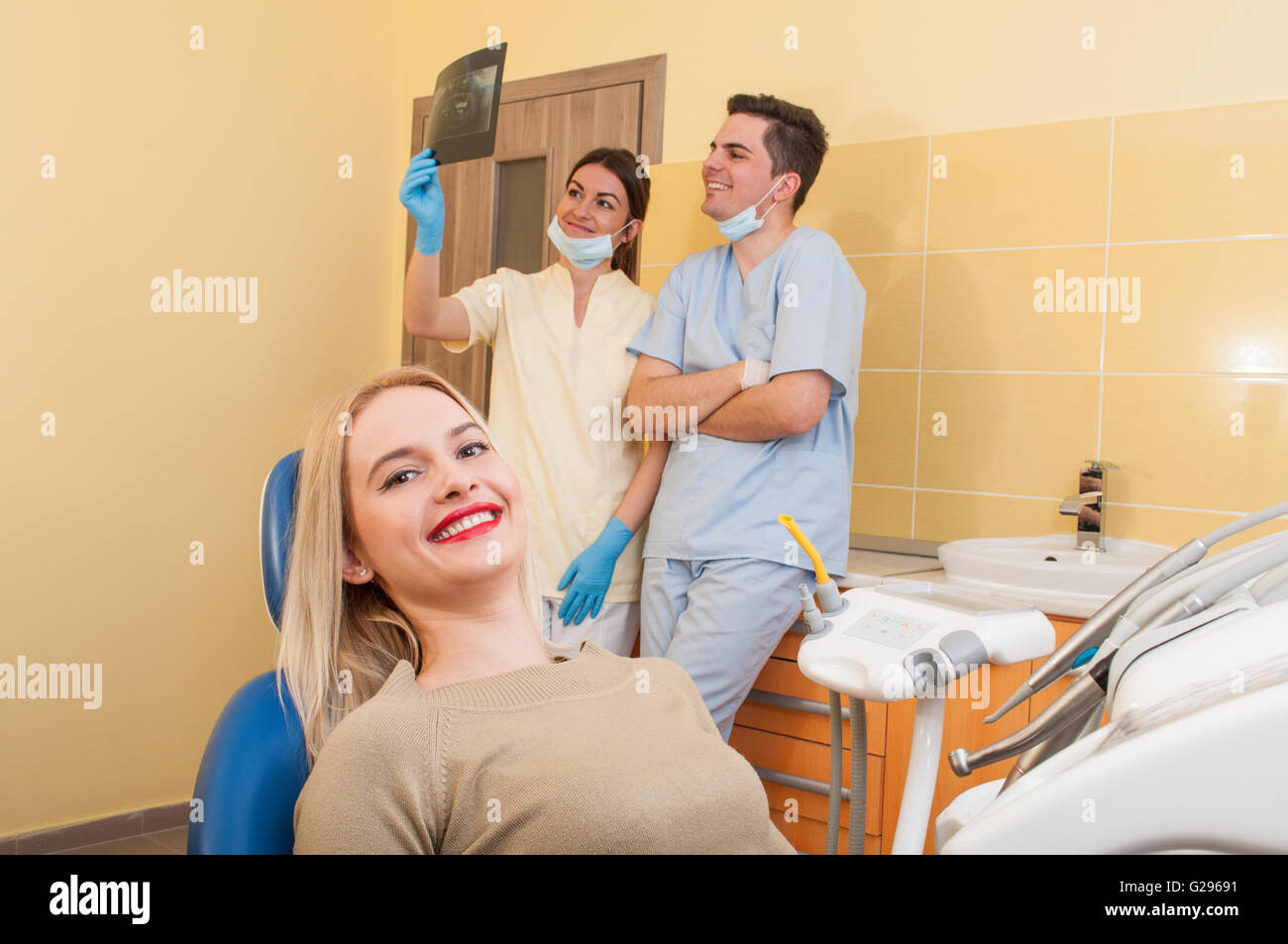 Satisfied dental team and beautiful smiling female patient Stock Photo
