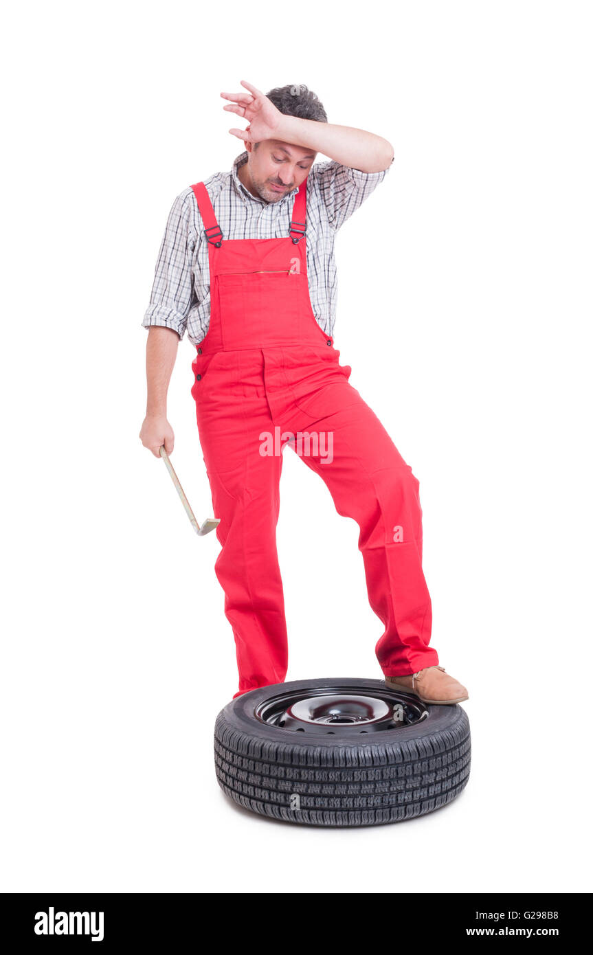 Tired mechanic after changing a new tire wiping his sweaty forehead Stock Photo
