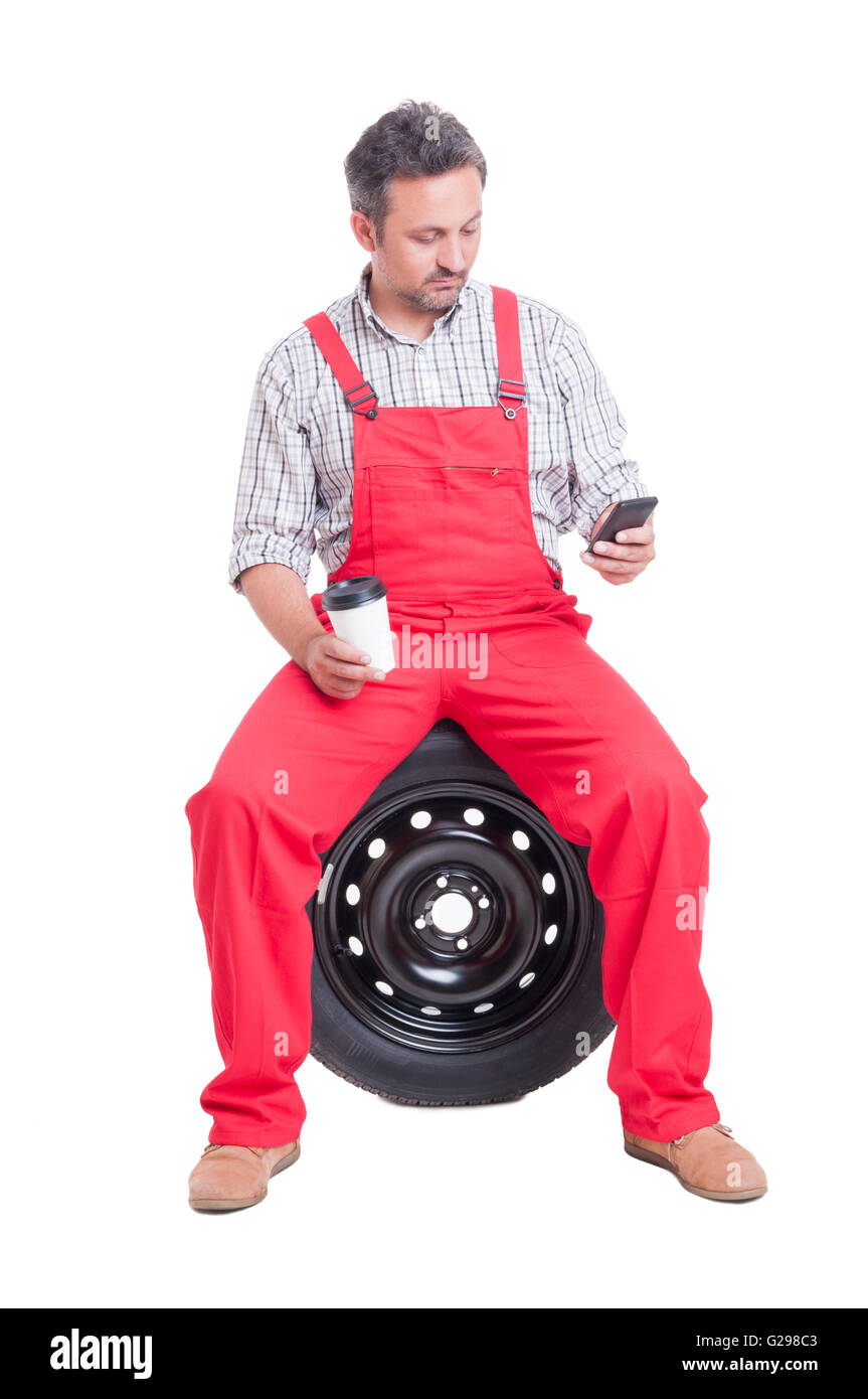 Auto mechanic texting or browsing on smartphone in coffee break Stock Photo
