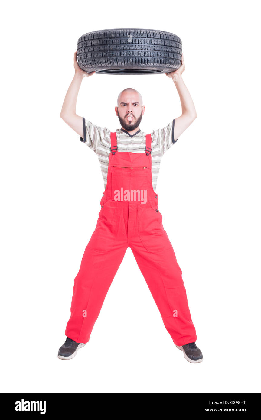 Mechanic lifting a car wheel above head with a mad angry face Stock Photo