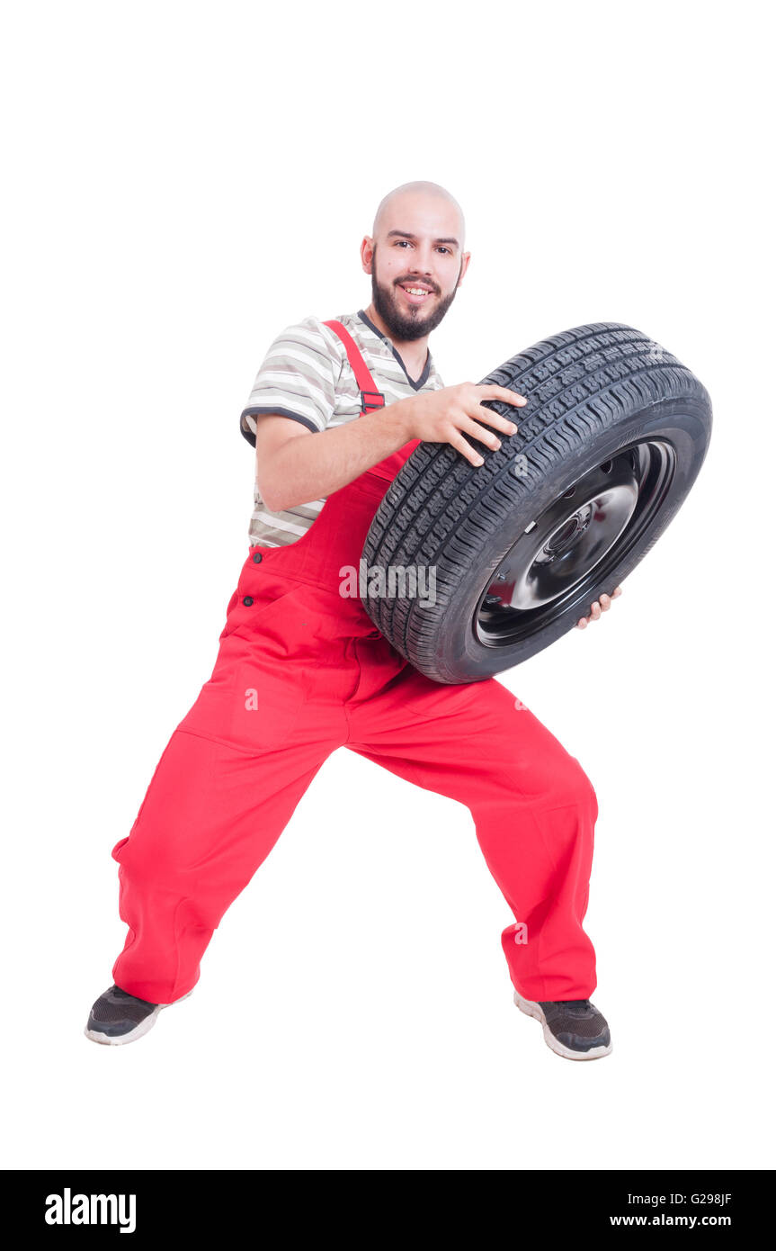 Smiling mechanic lifting a heavy car wheel isolated on white Stock ...