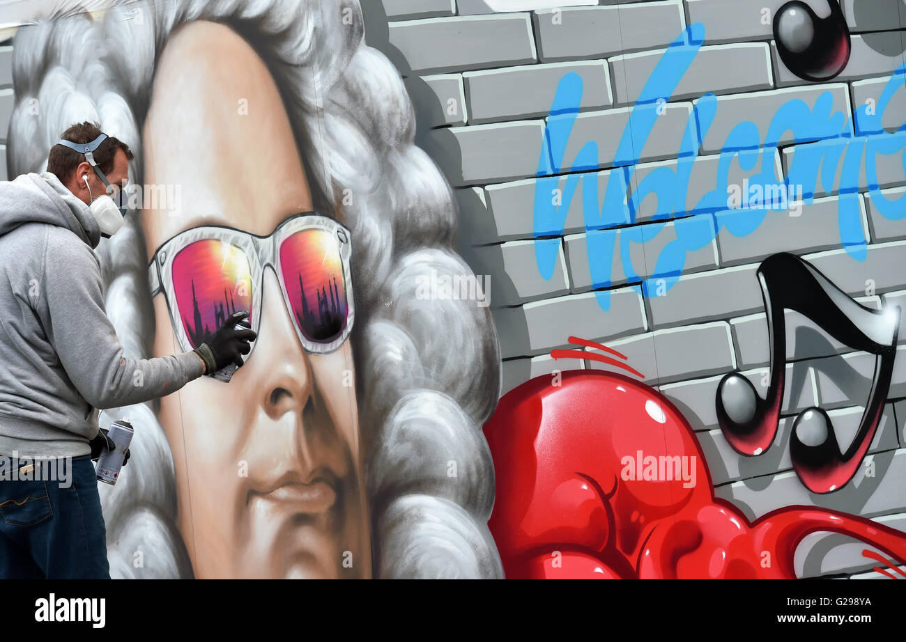 The portrait of the composer Georg Friedrich Haendel is fashioned by the Halle graffiti artist Michael Gensen at the market in Halle/Saale, Germany, 25 May 2016. With colourful sunglasses, in which the striking silhouette of the city is reflected, the motif of the festival can be seen on an information box. Under the motto "Haendel beruehrt" (lt. "Touched by Haendel") the renowned festival of Baroque music starts on 25 May 2016 and offers 17 days high profile events. Photo: Hendrik Schmidt/ZB Stock Photo